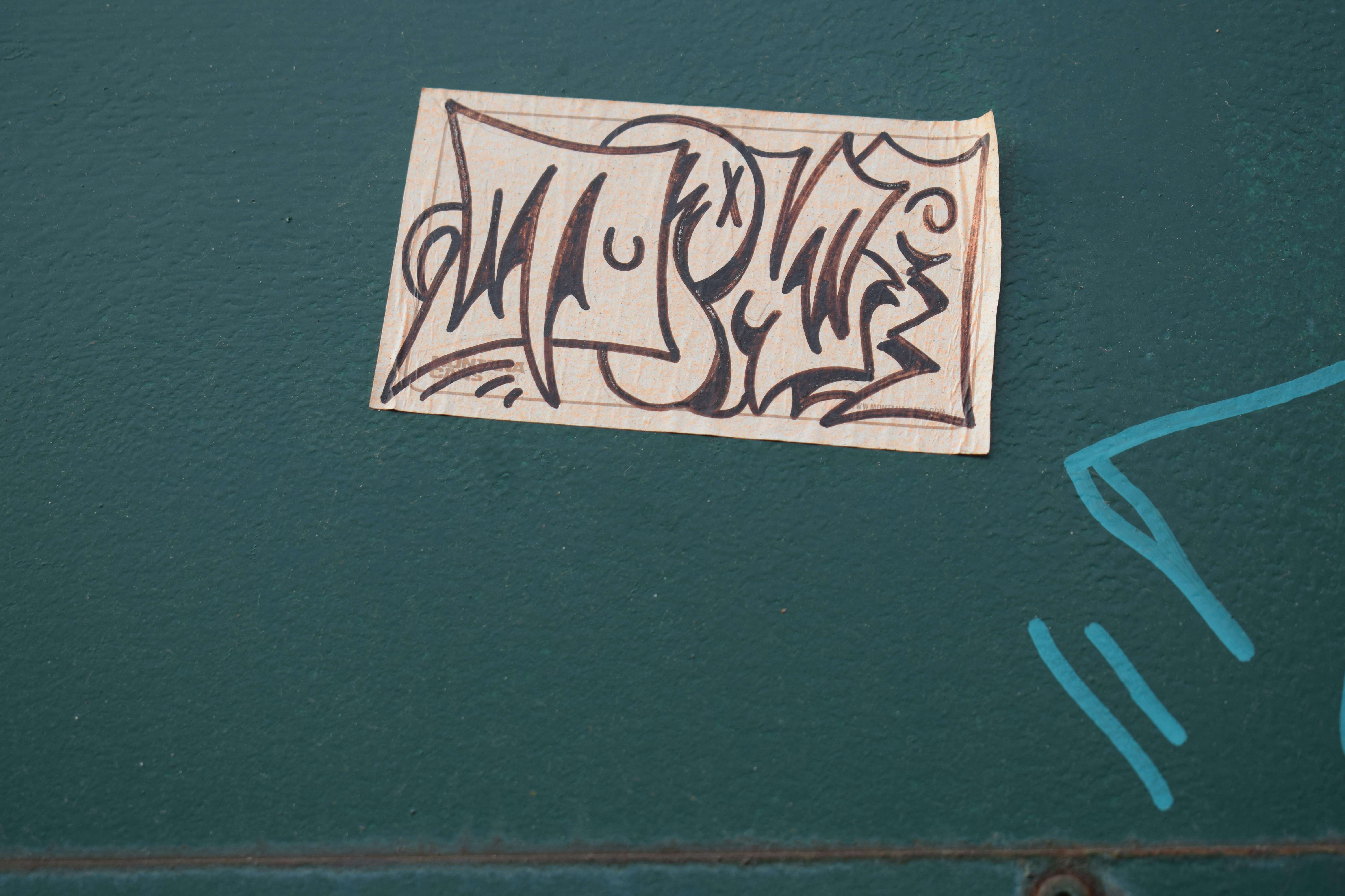 Graffiti tag on a teal wall with blue lines