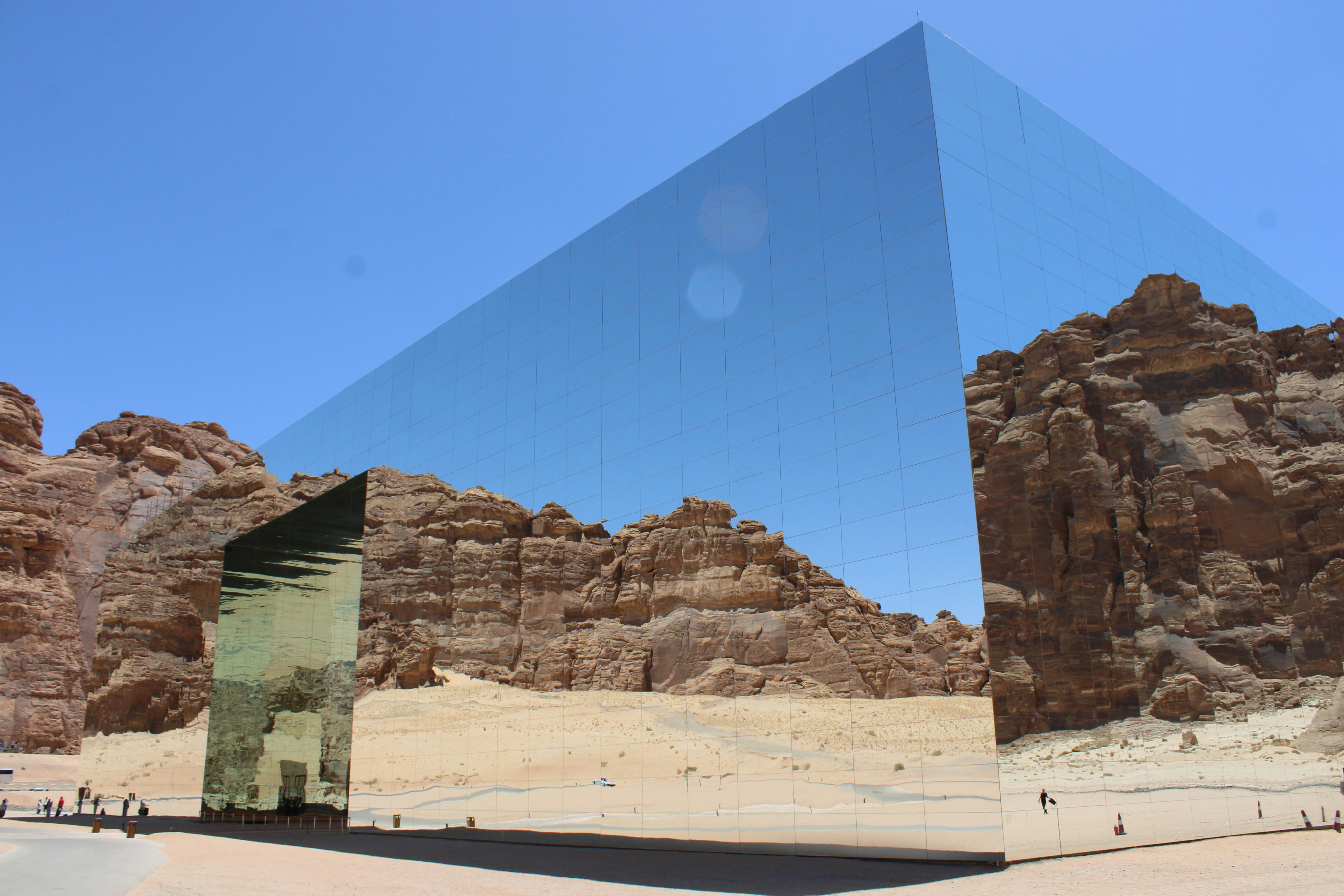 Mirrored structure reflects desert mountains and blue sky