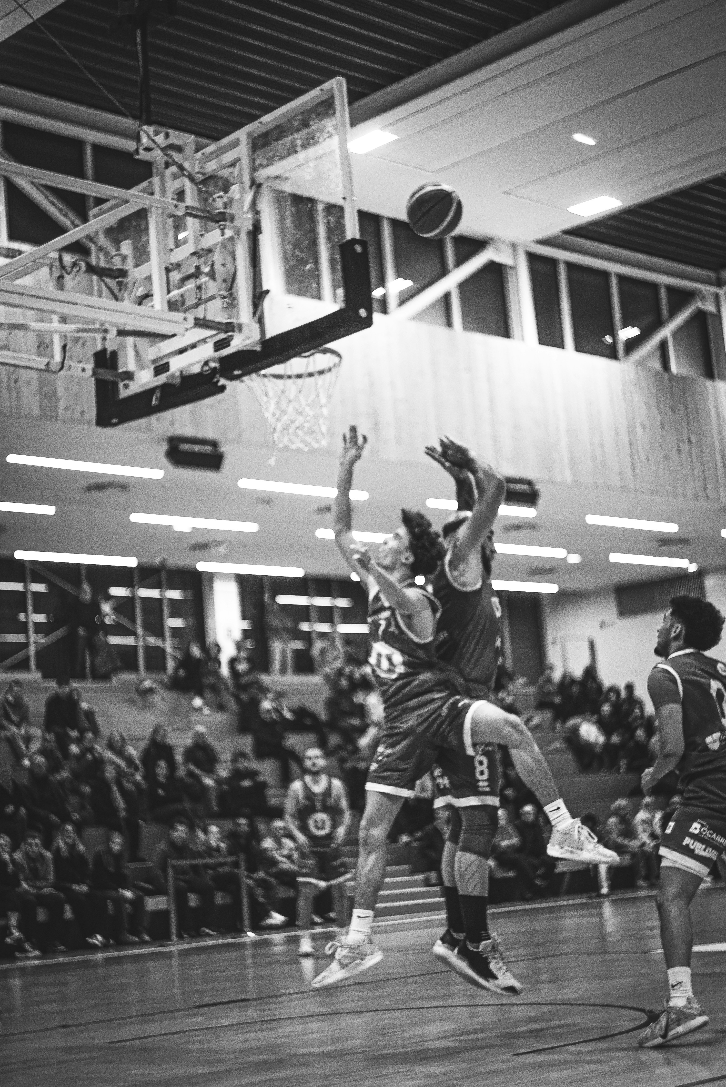 Pemain bola basket melompat untuk mendapatkan bola di dekat ring.