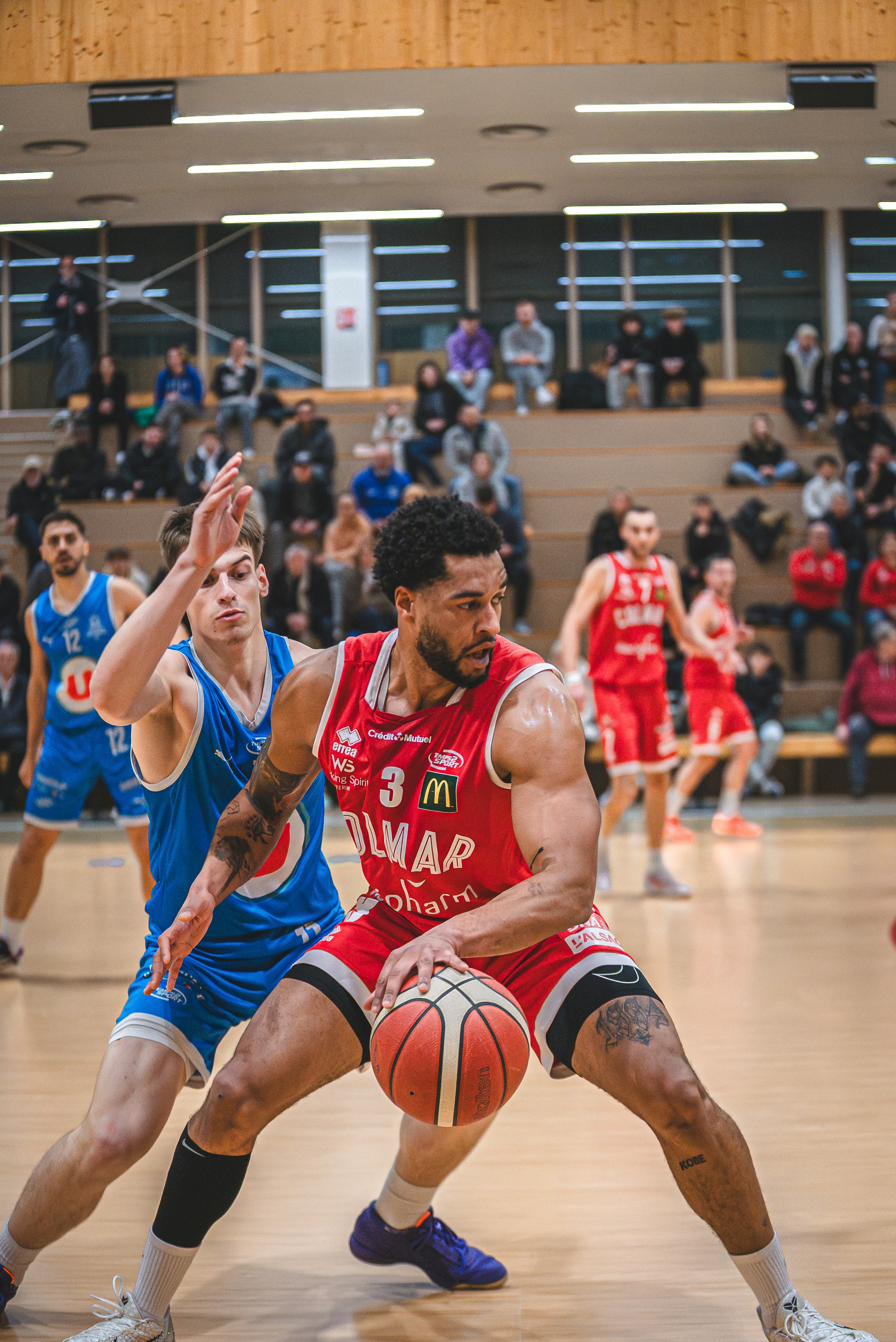 Basketball player in red jersey dribbles ball past defender