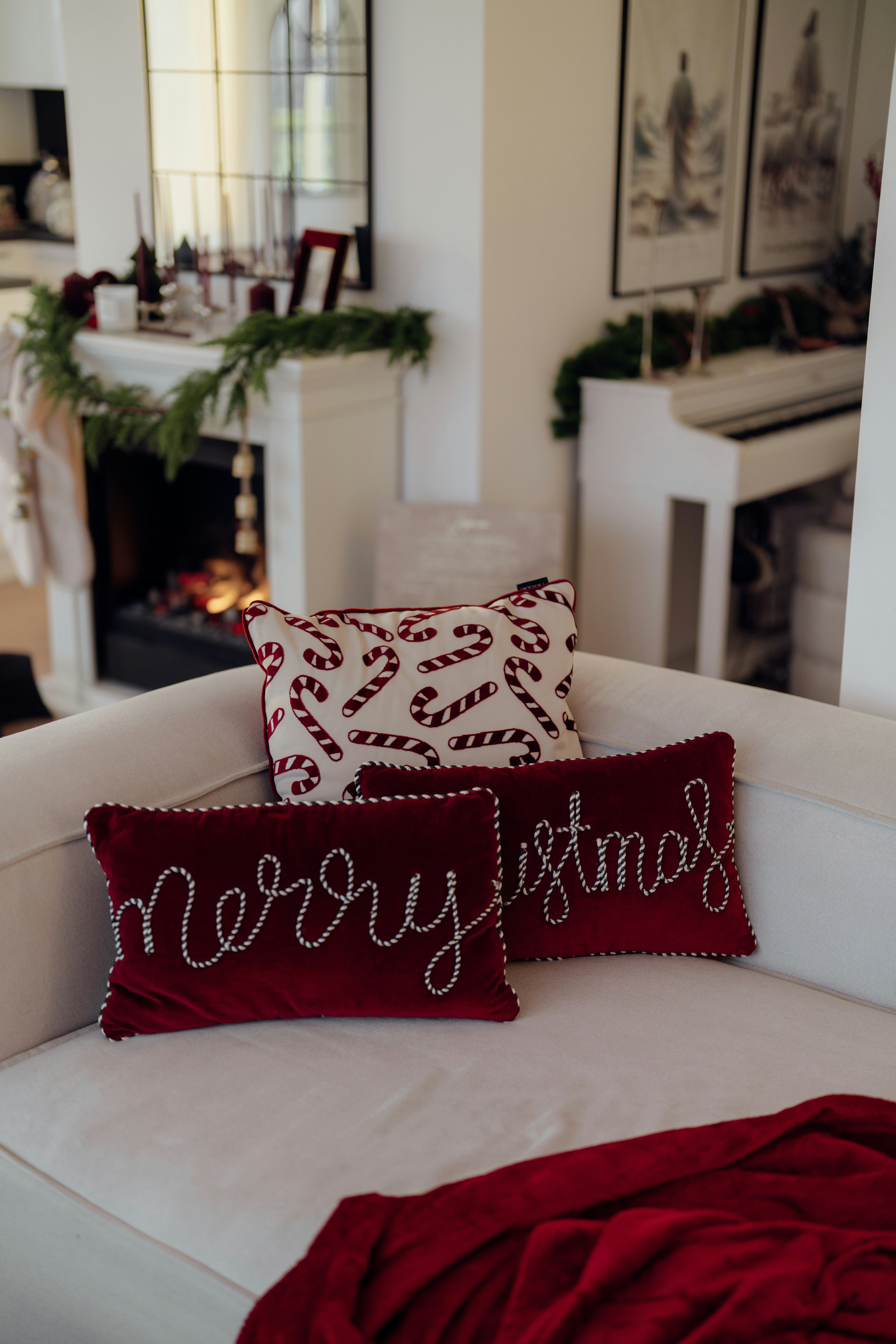 Christmas pillows on a white sofa with fireplace.