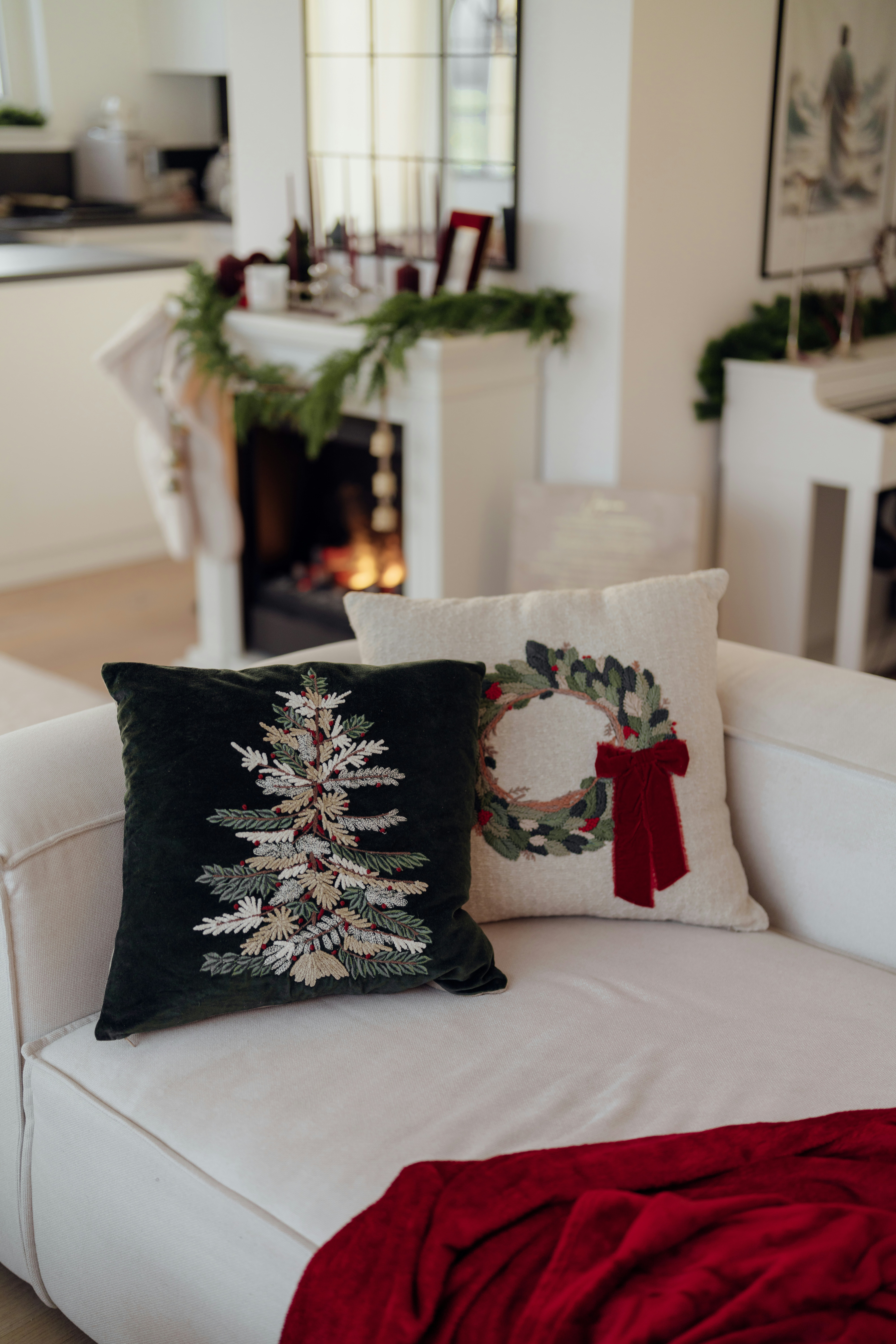 Festive christmas pillows on a white couch with fireplace.