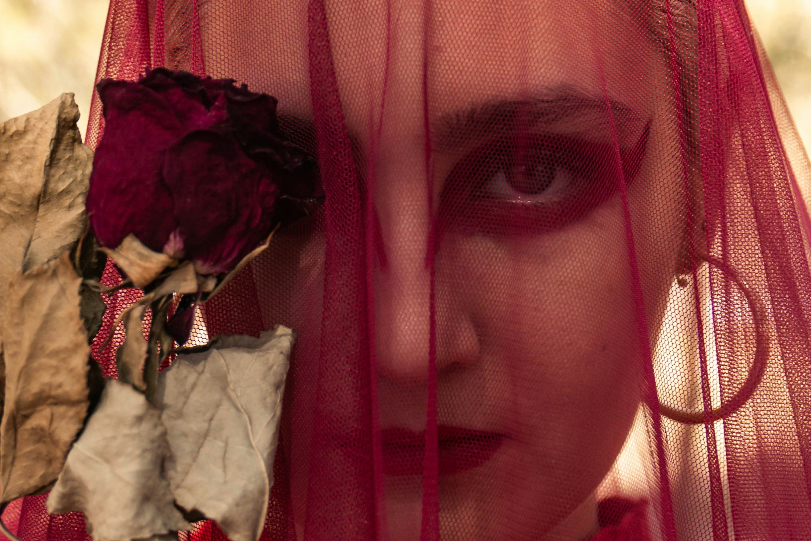 Woman with dramatic makeup behind red veil