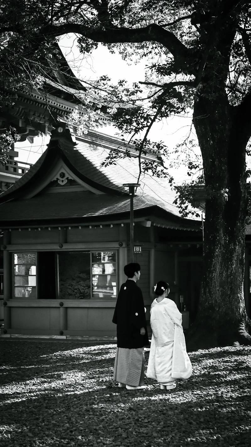 A couple in wedding kimono at a shrine, in black and white