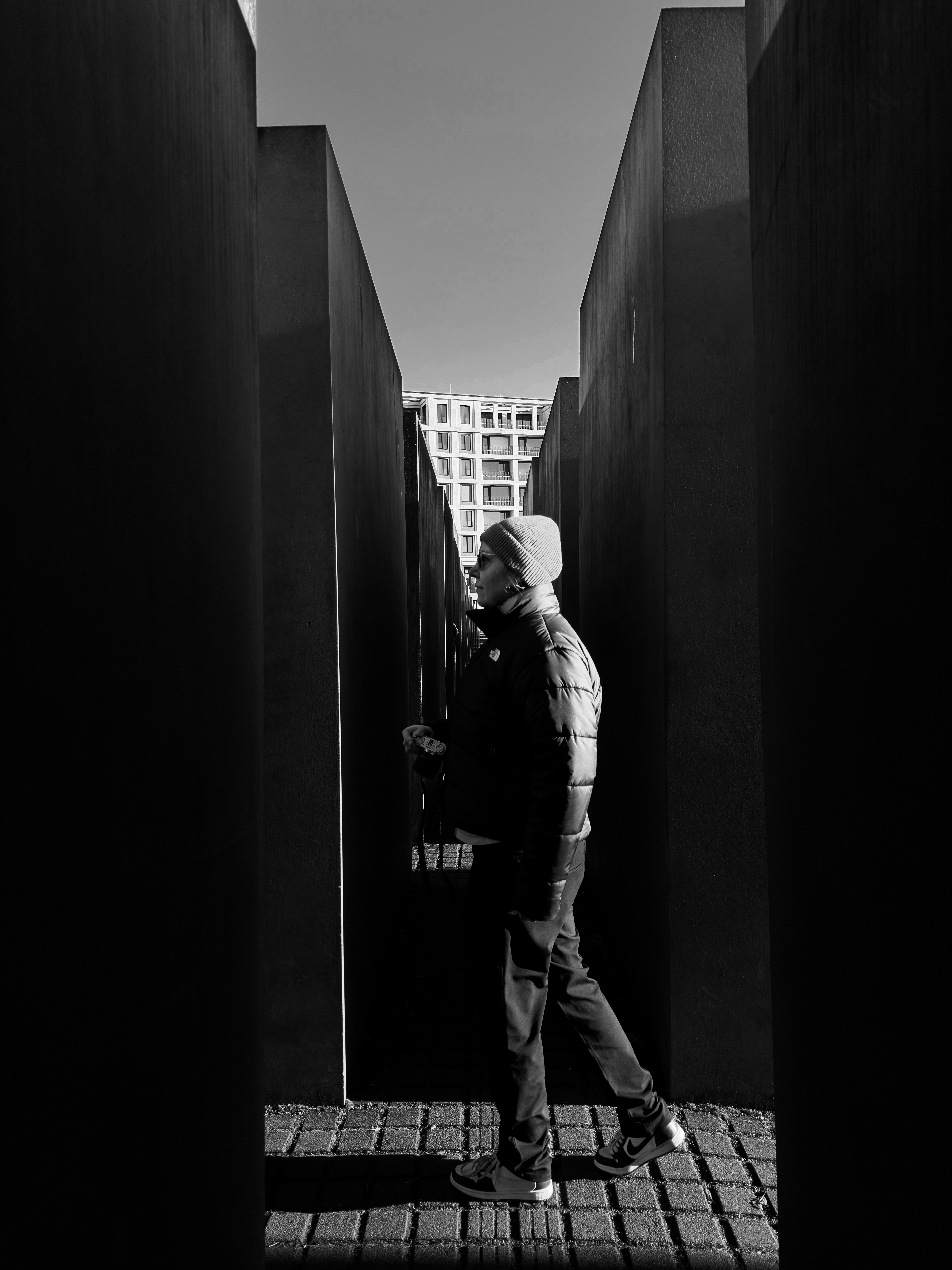 Man walking between tall dark concrete blocks