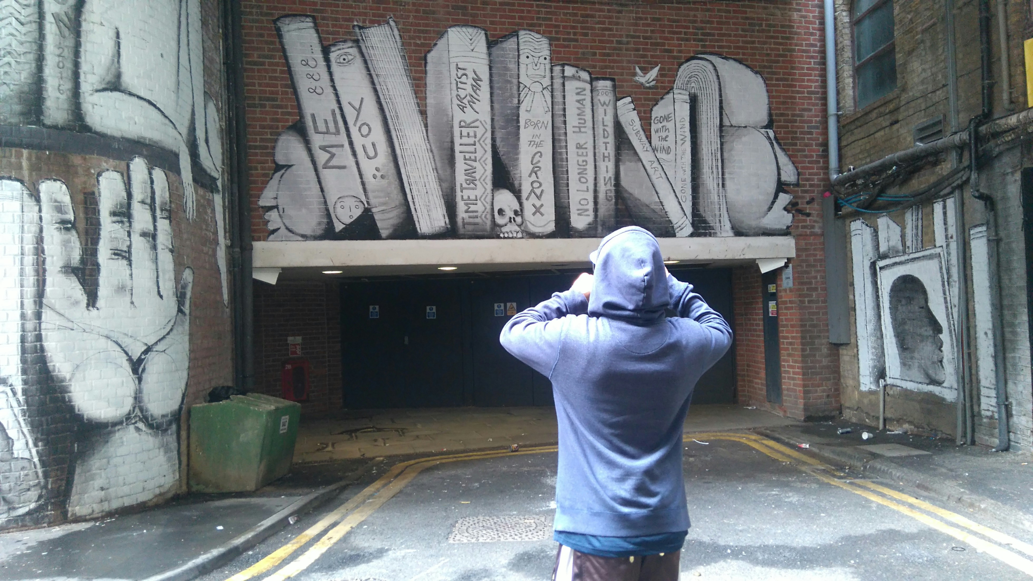 Person stands before graffiti art of books