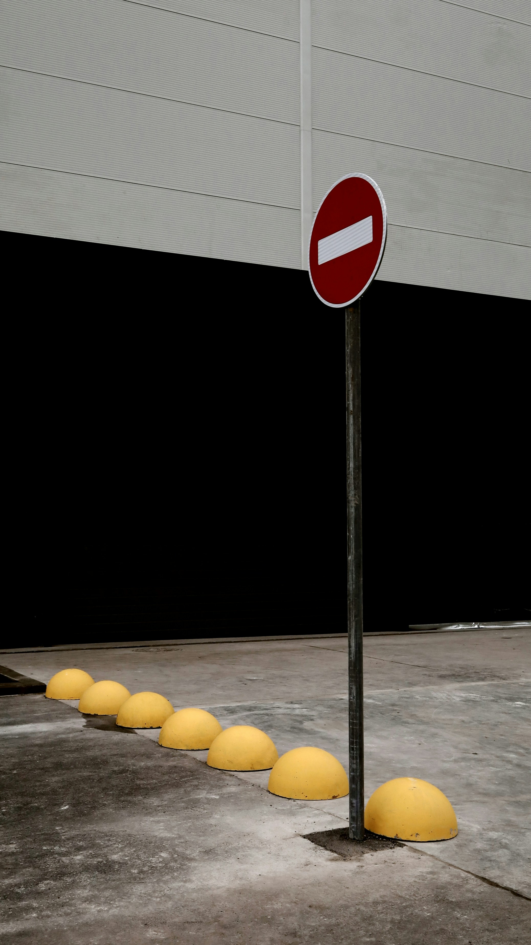 A no entry sign stands by yellow bollards.