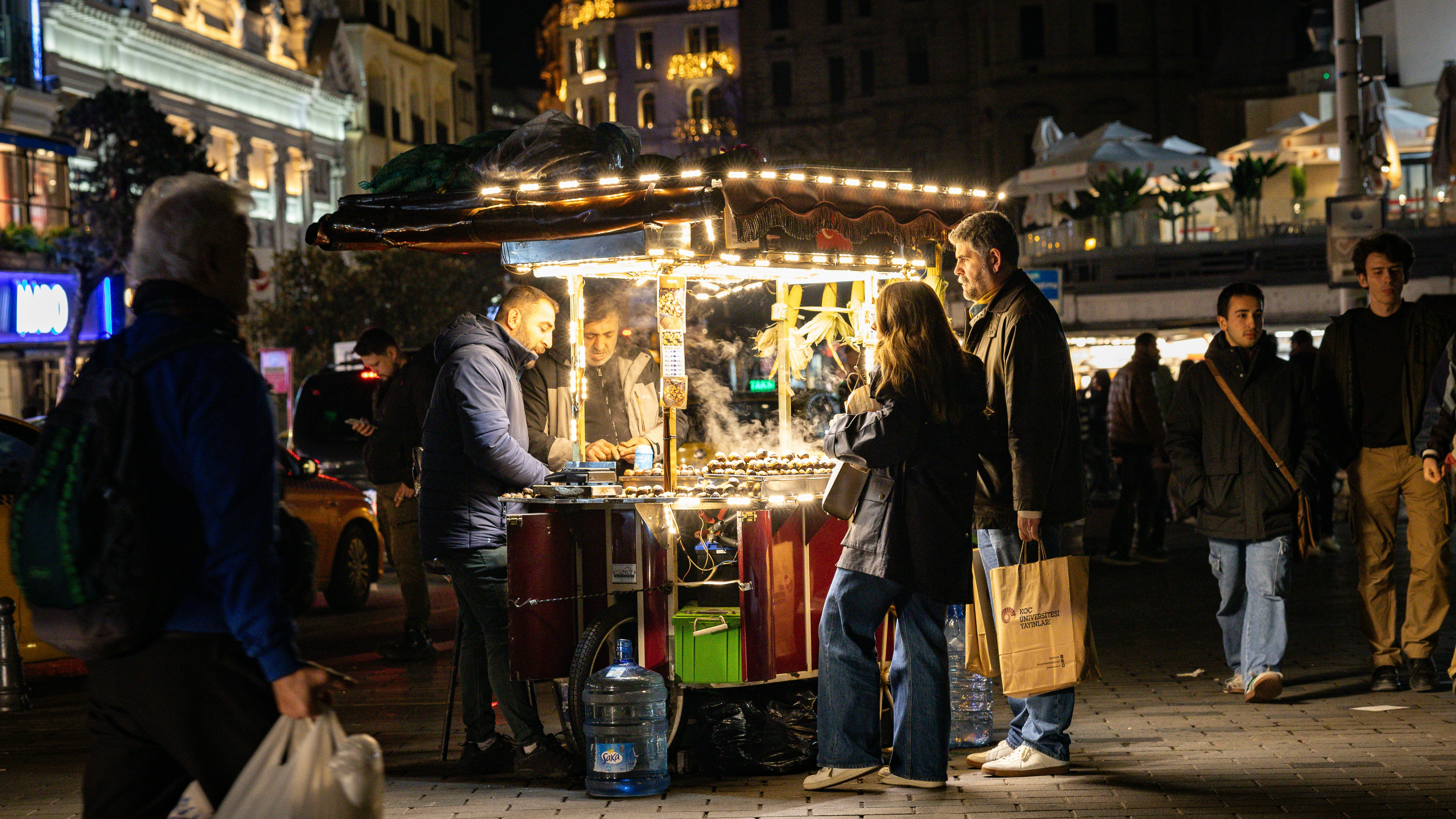 People gather around a street food cart at night.