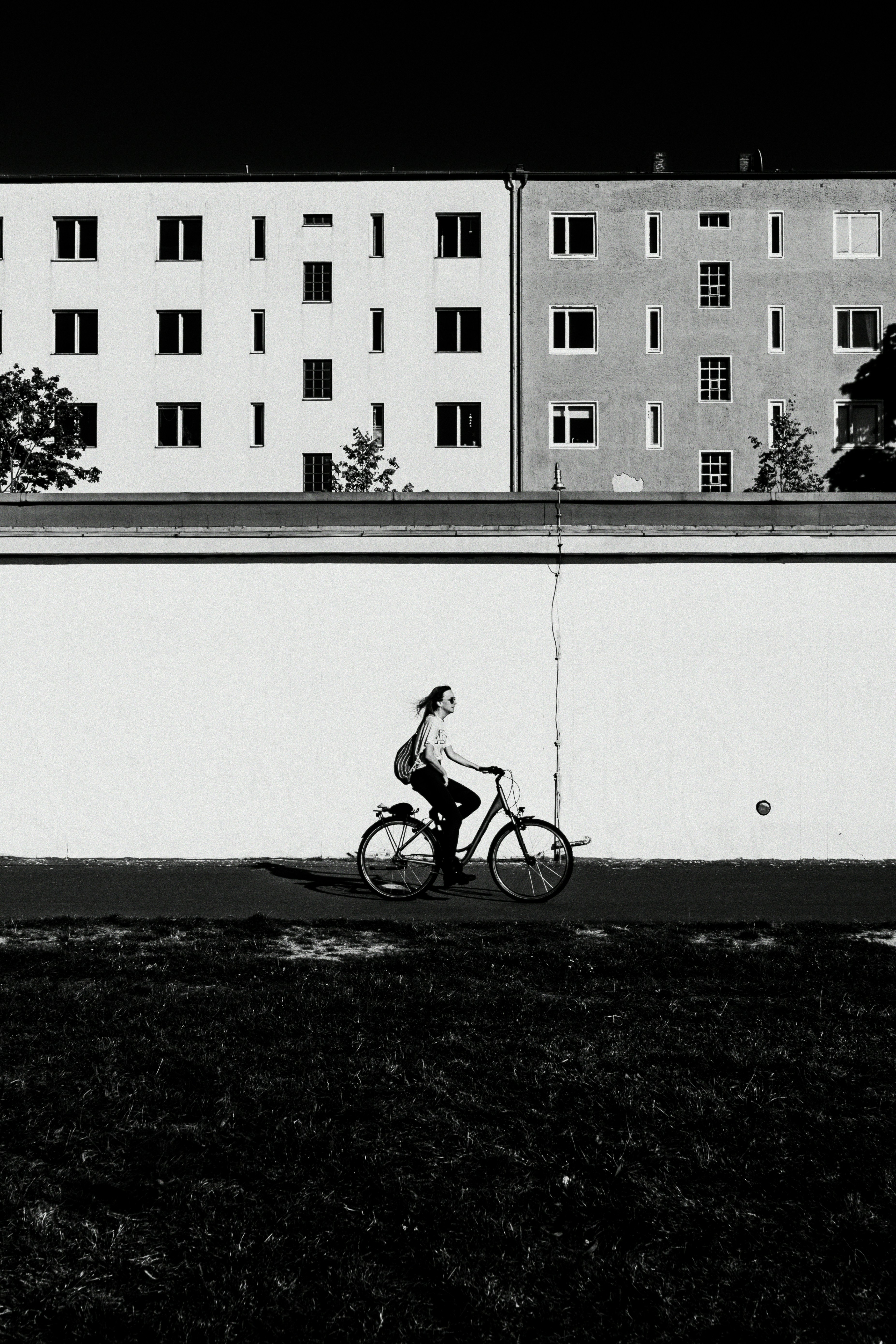 Woman riding bicycle past apartment buildings