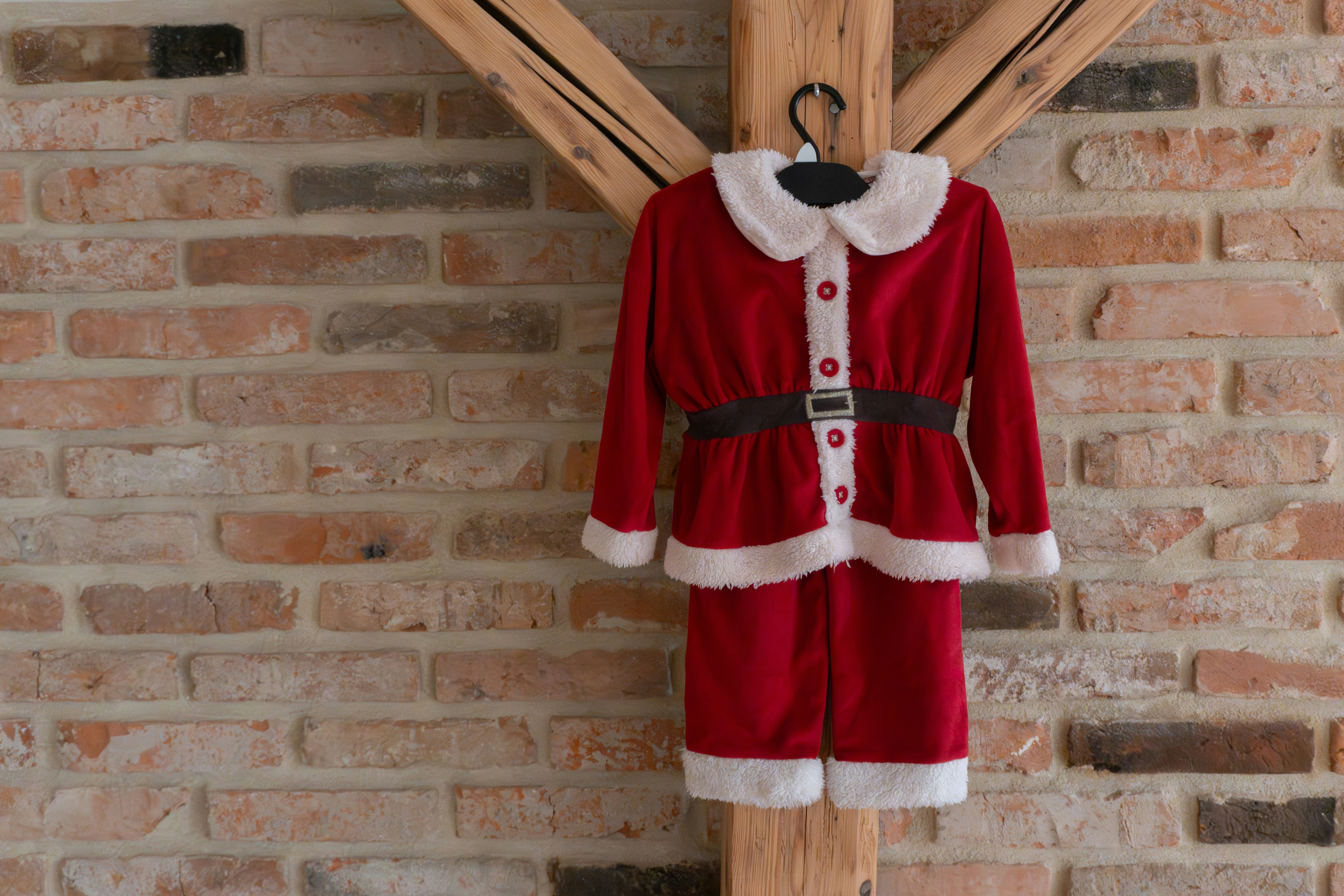 A child's santa claus costume hangs on a wall.