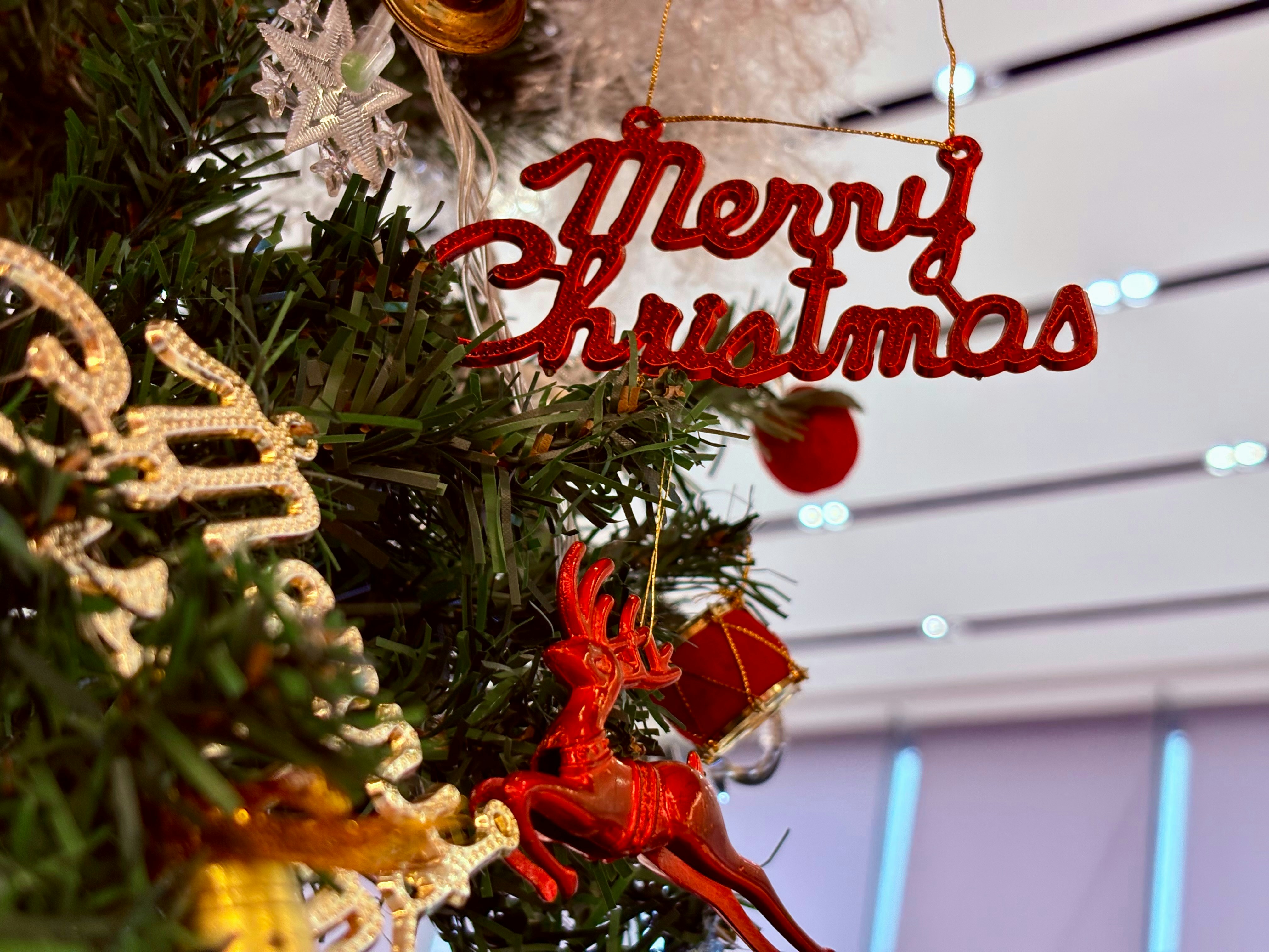 Merry christmas ornament on a decorated tree