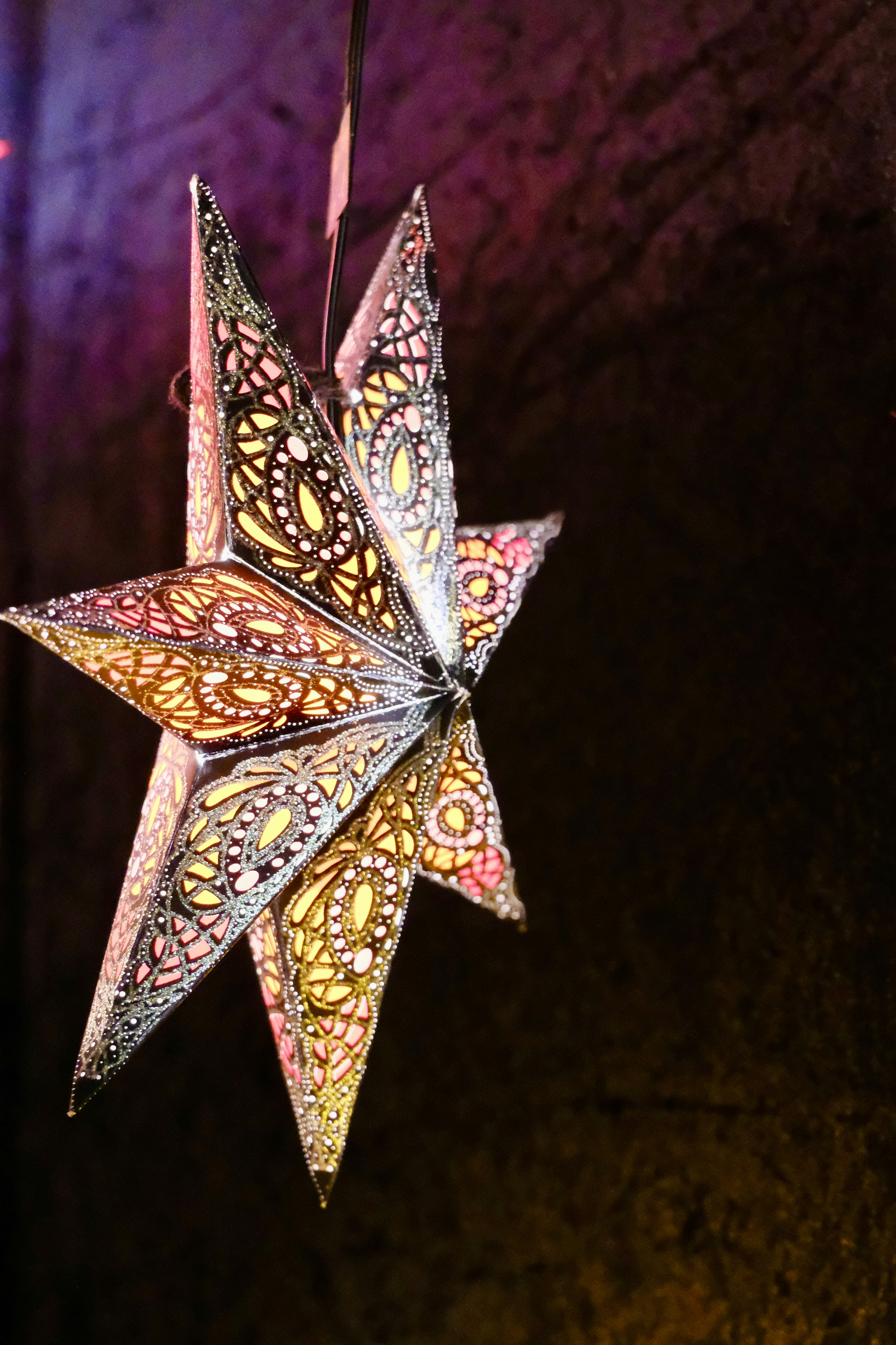 Ornate star lantern with intricate cutouts glows softly.