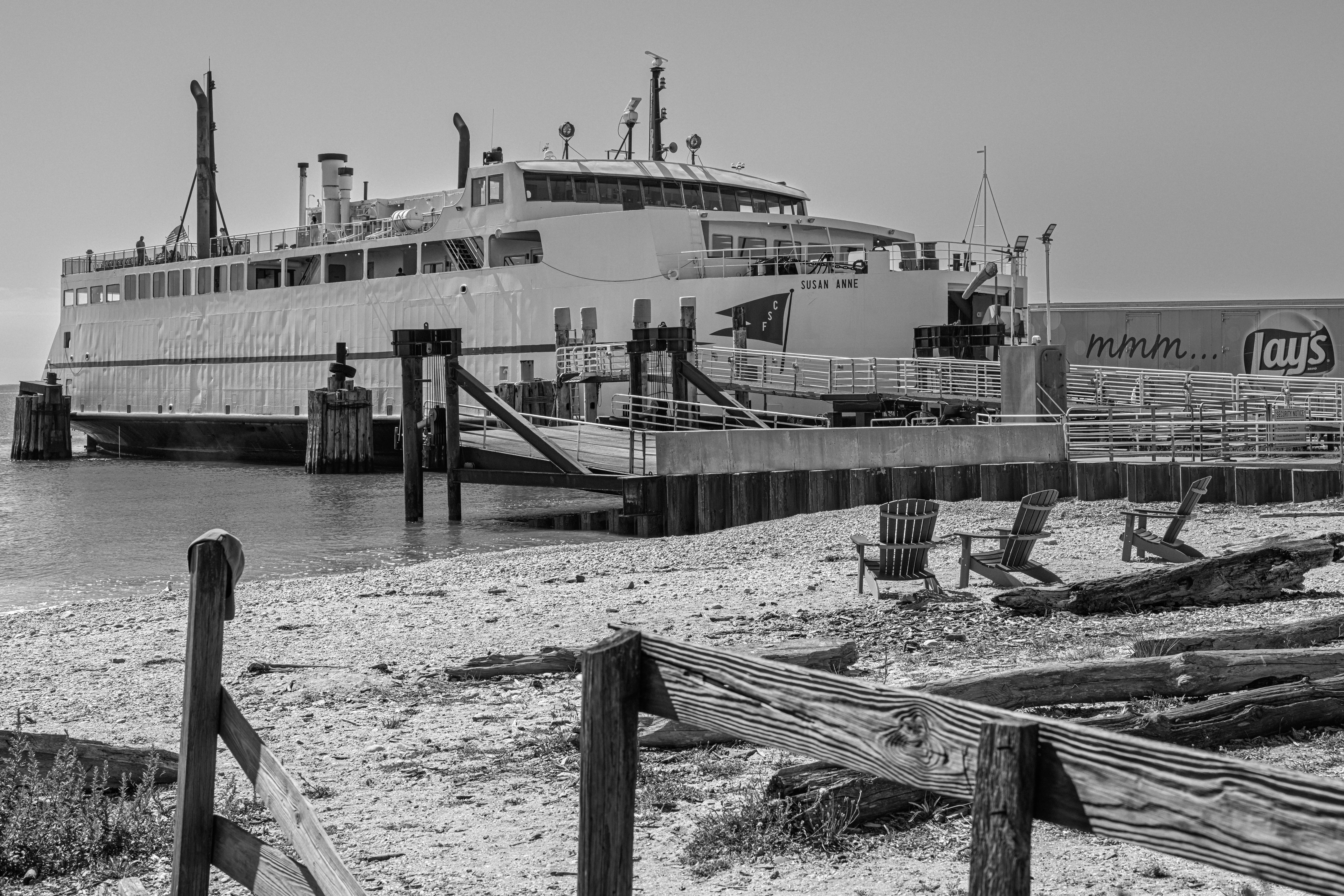 Large ferry docked at a pier with beach chairs.