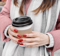 Woman holding a coffee cup with red nails