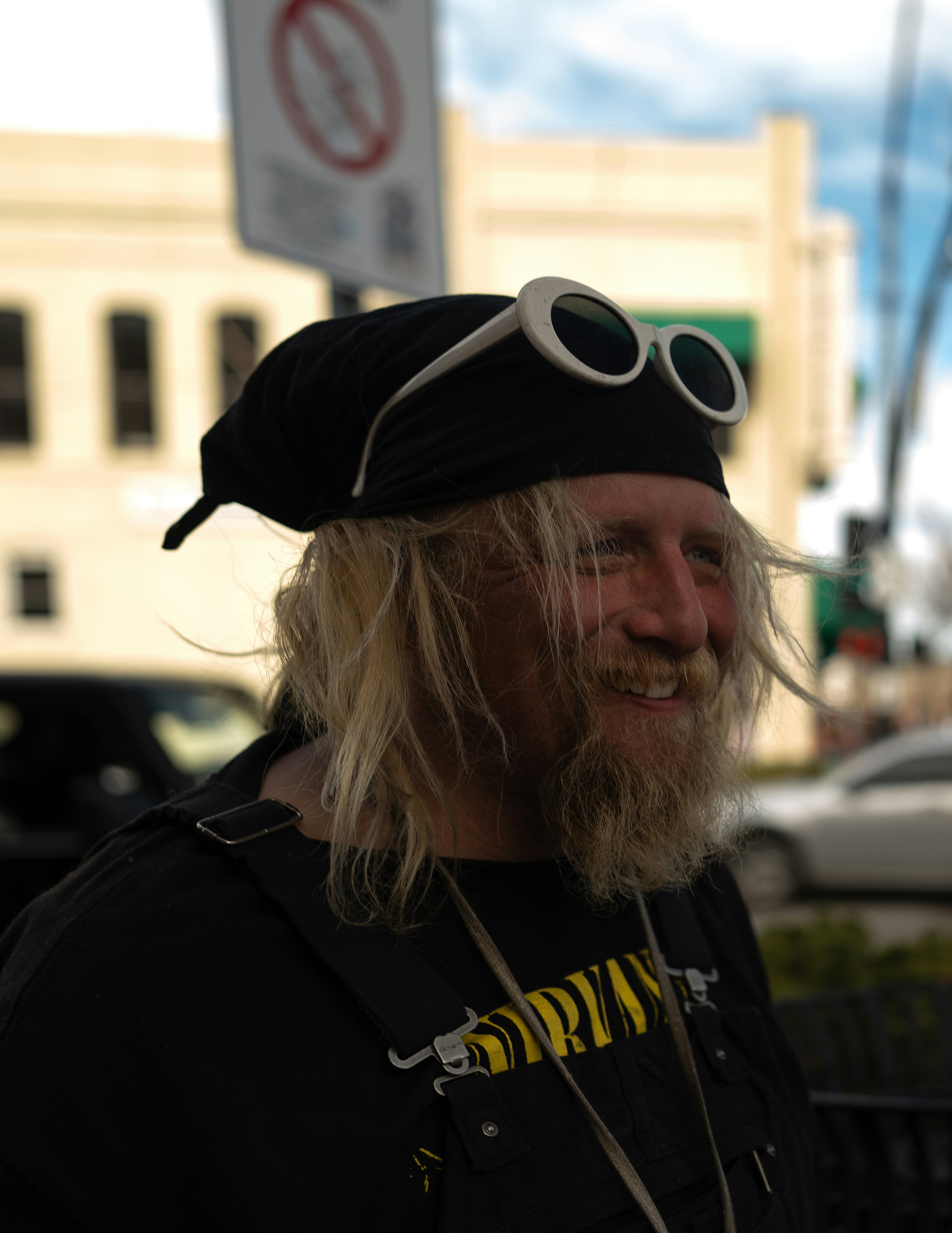 Man with bandana, sunglasses, and beard smiles