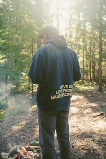 Man in hoodie near campfire in forest