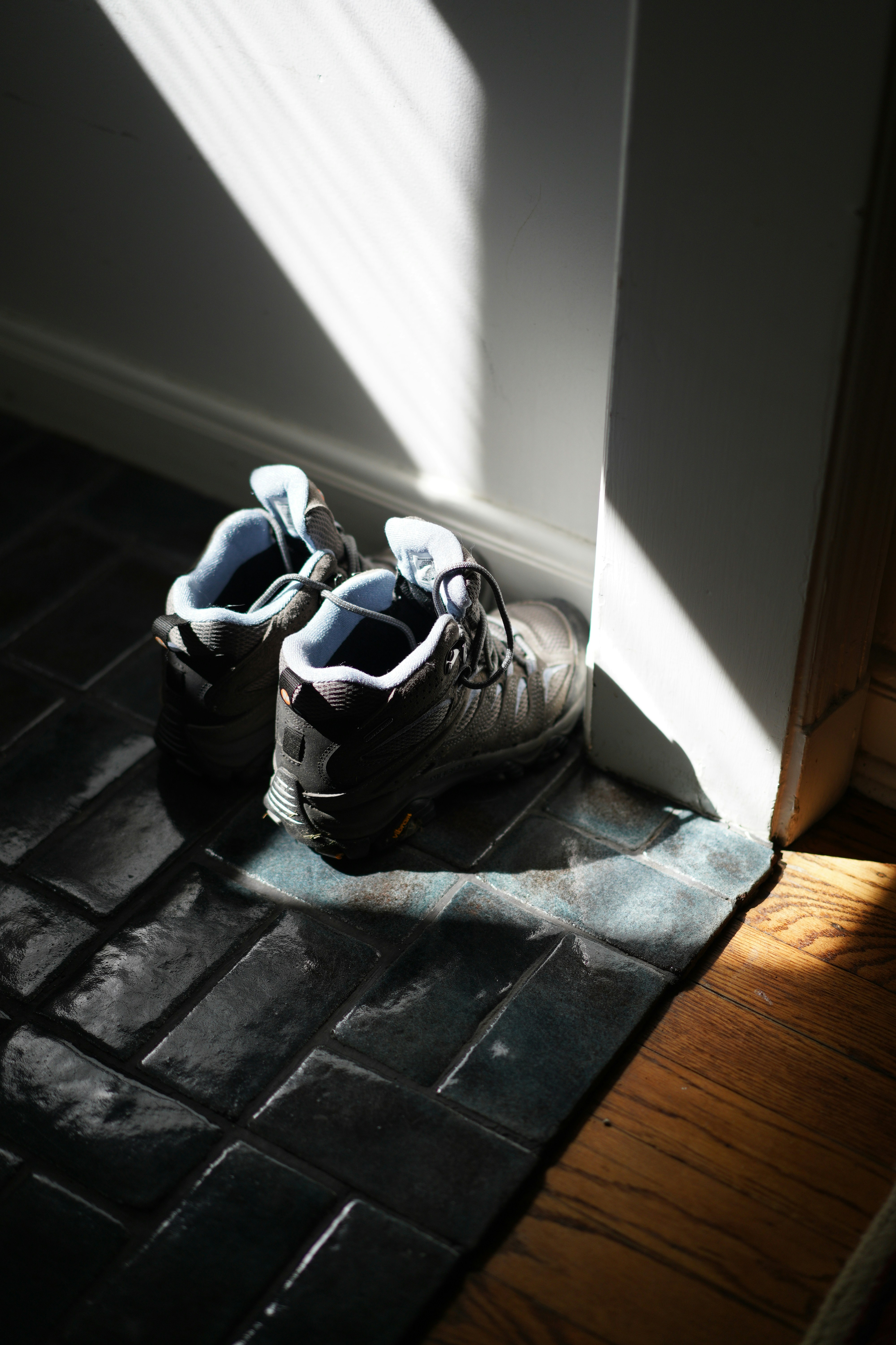 A pair of hiking boots on a tiled floor.