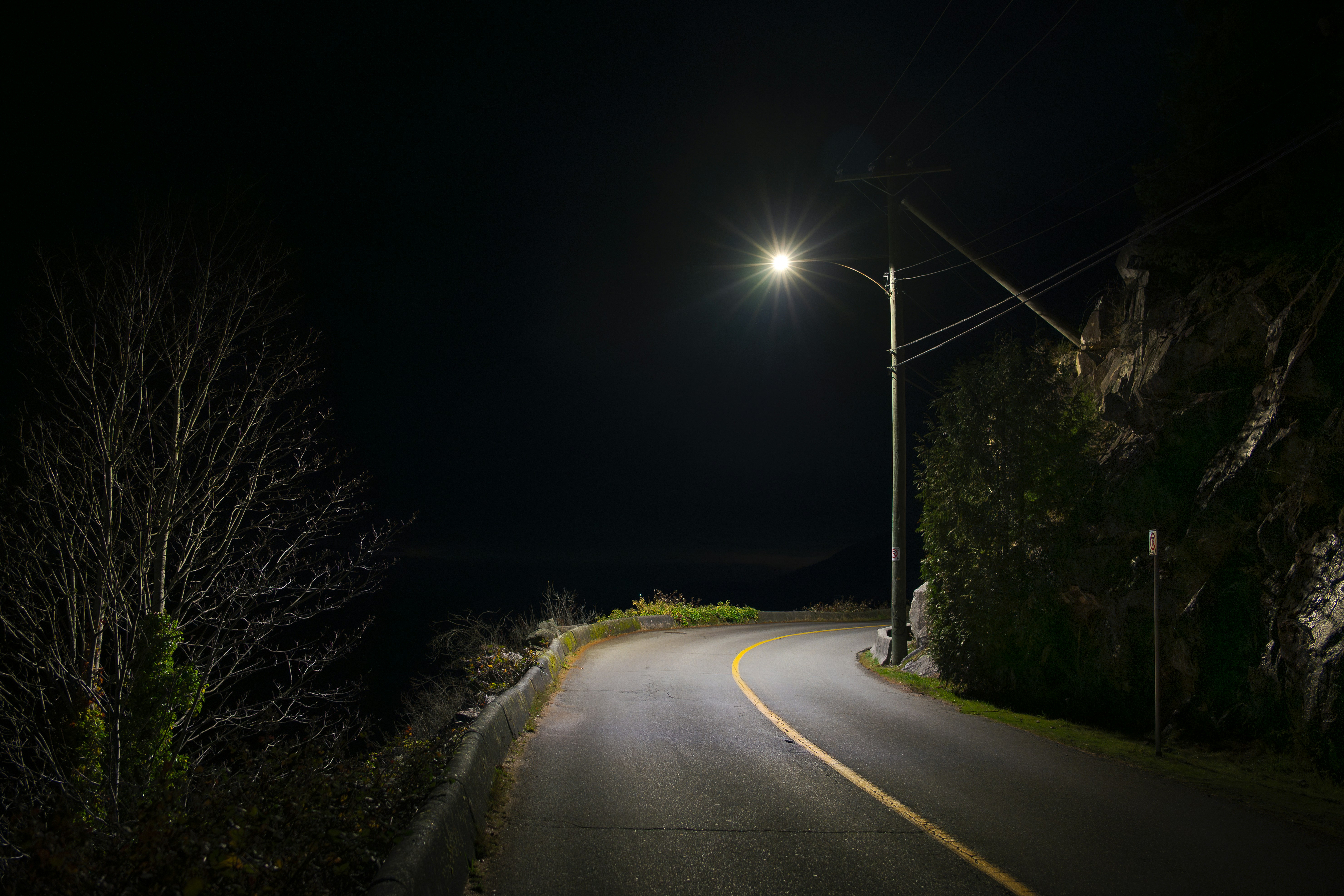 Empty road at night with a single street light.