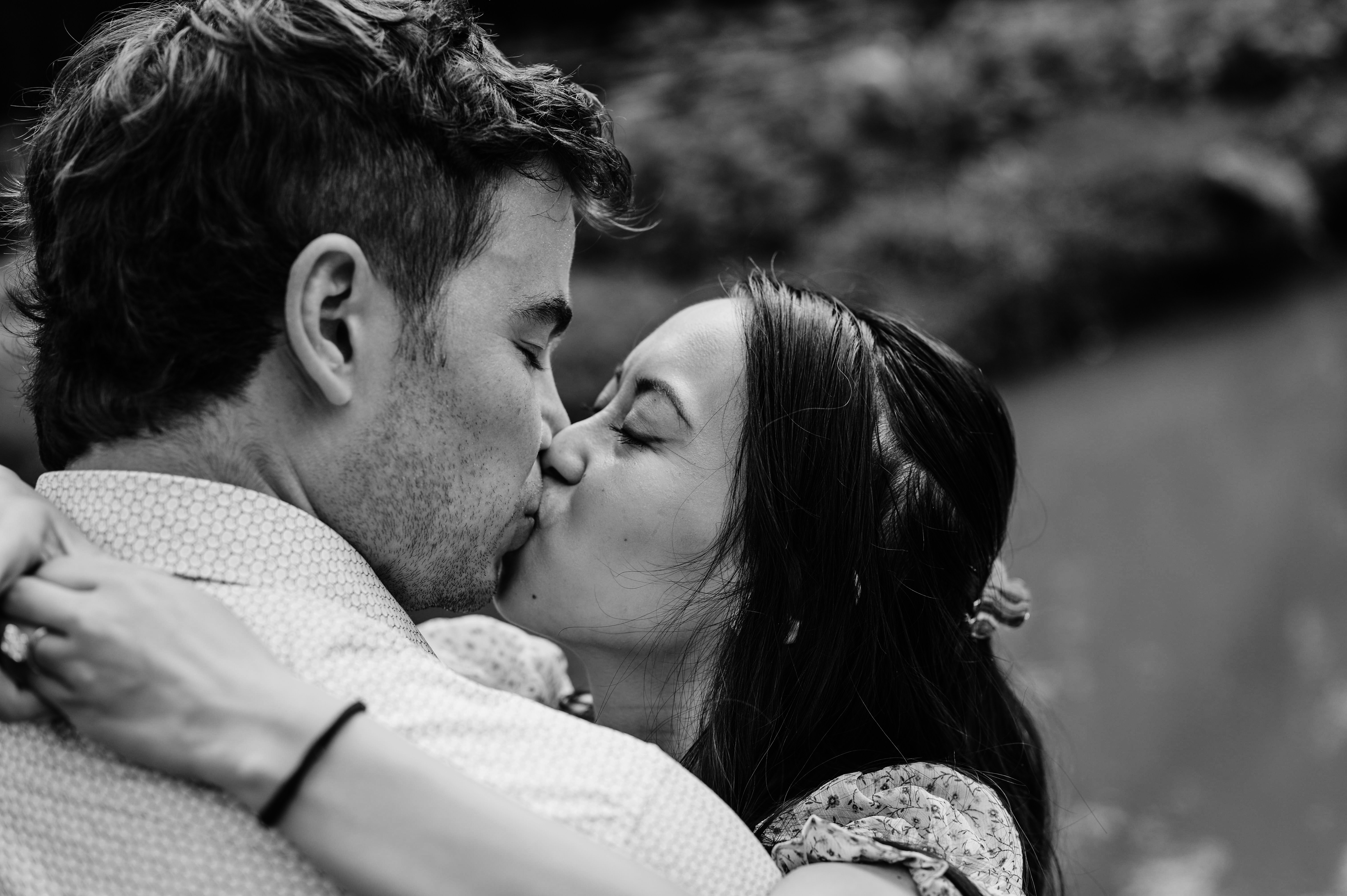 A couple kissing passionately in a black and white setting.