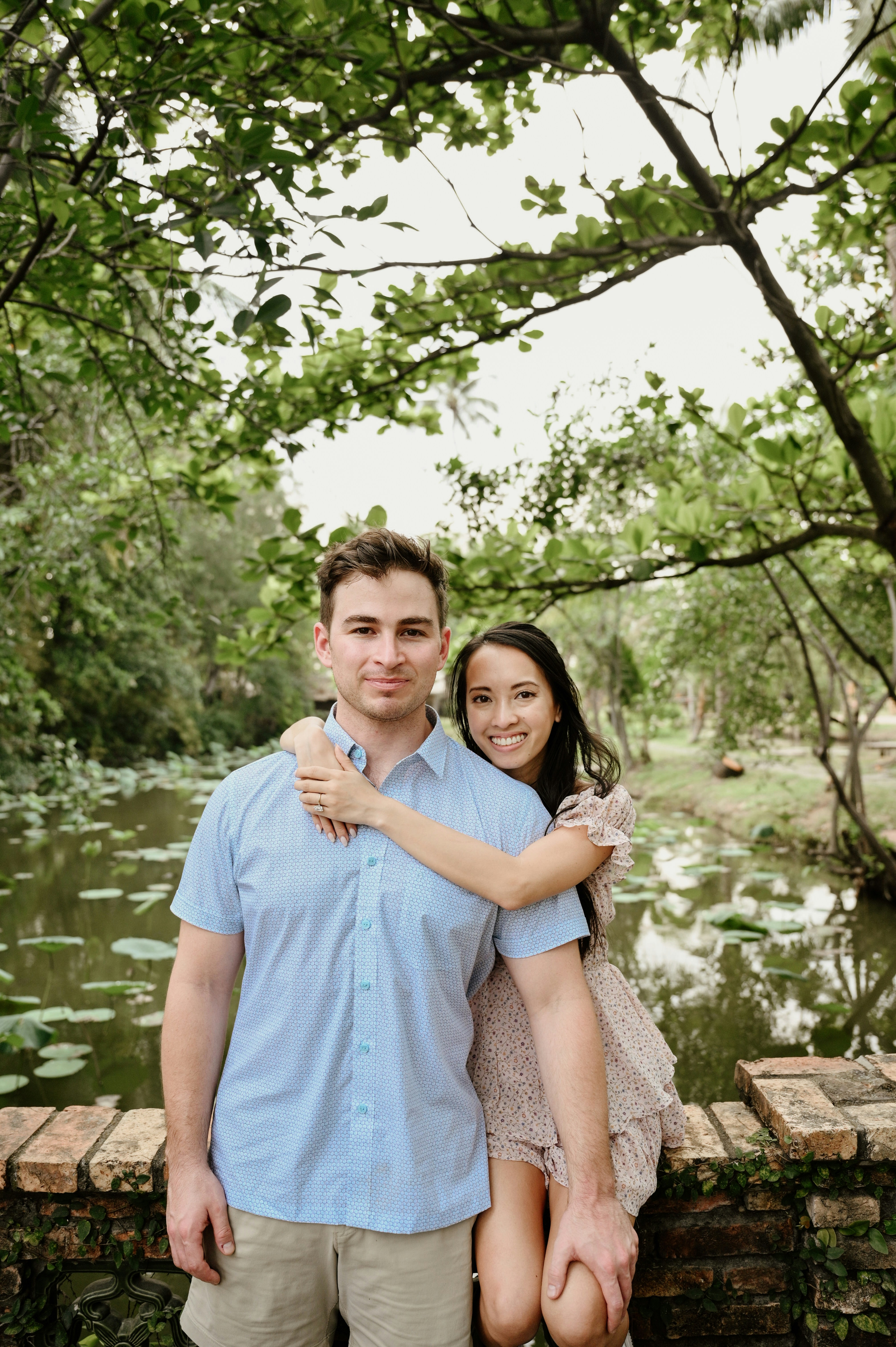 Couple posing by a pond with lily pads.