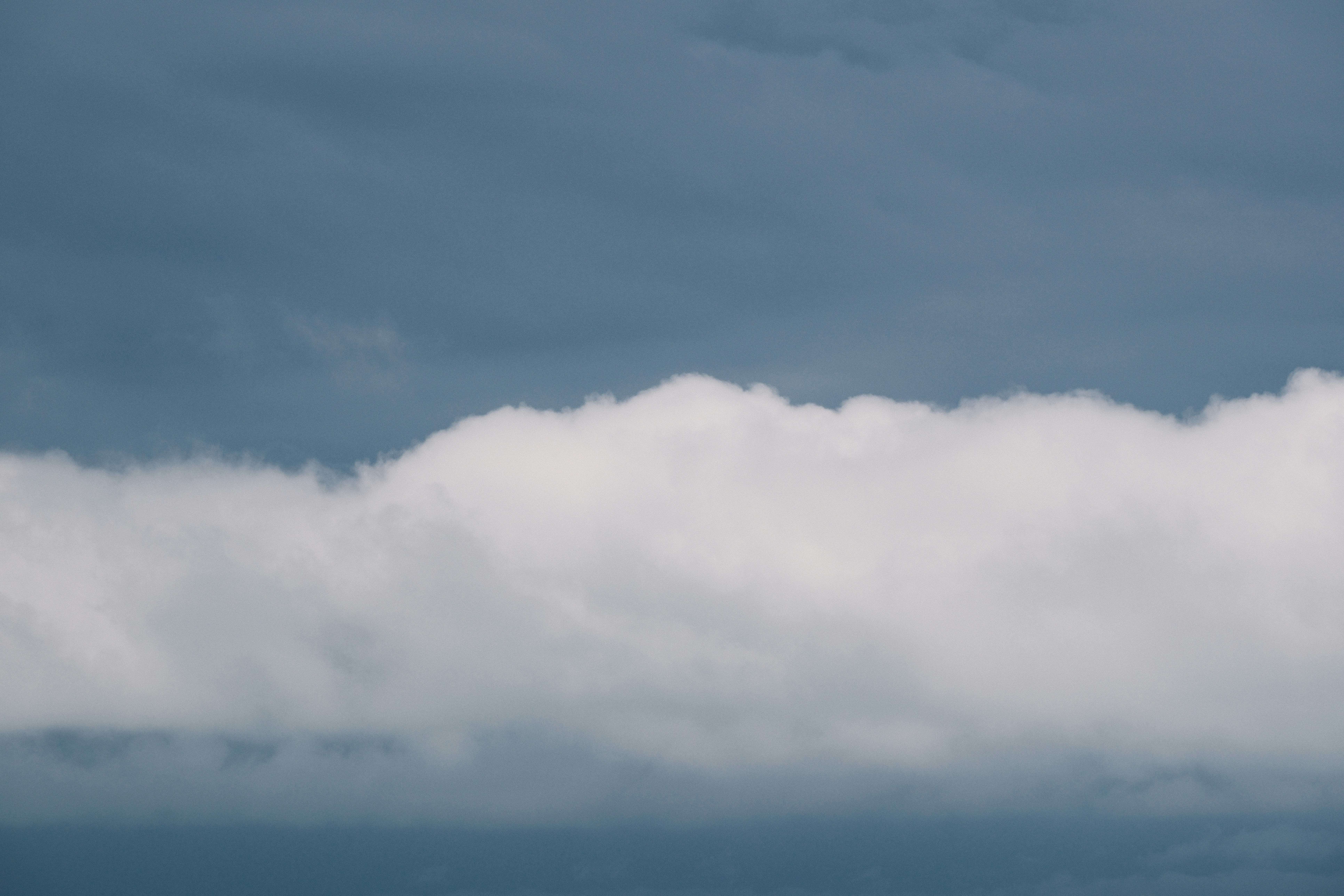 A thick band of white clouds against a dark sky.