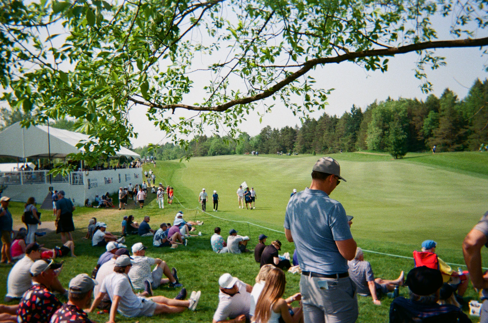 Spectators lining a fairway as golfers play at a tournament in Ontario, Canada