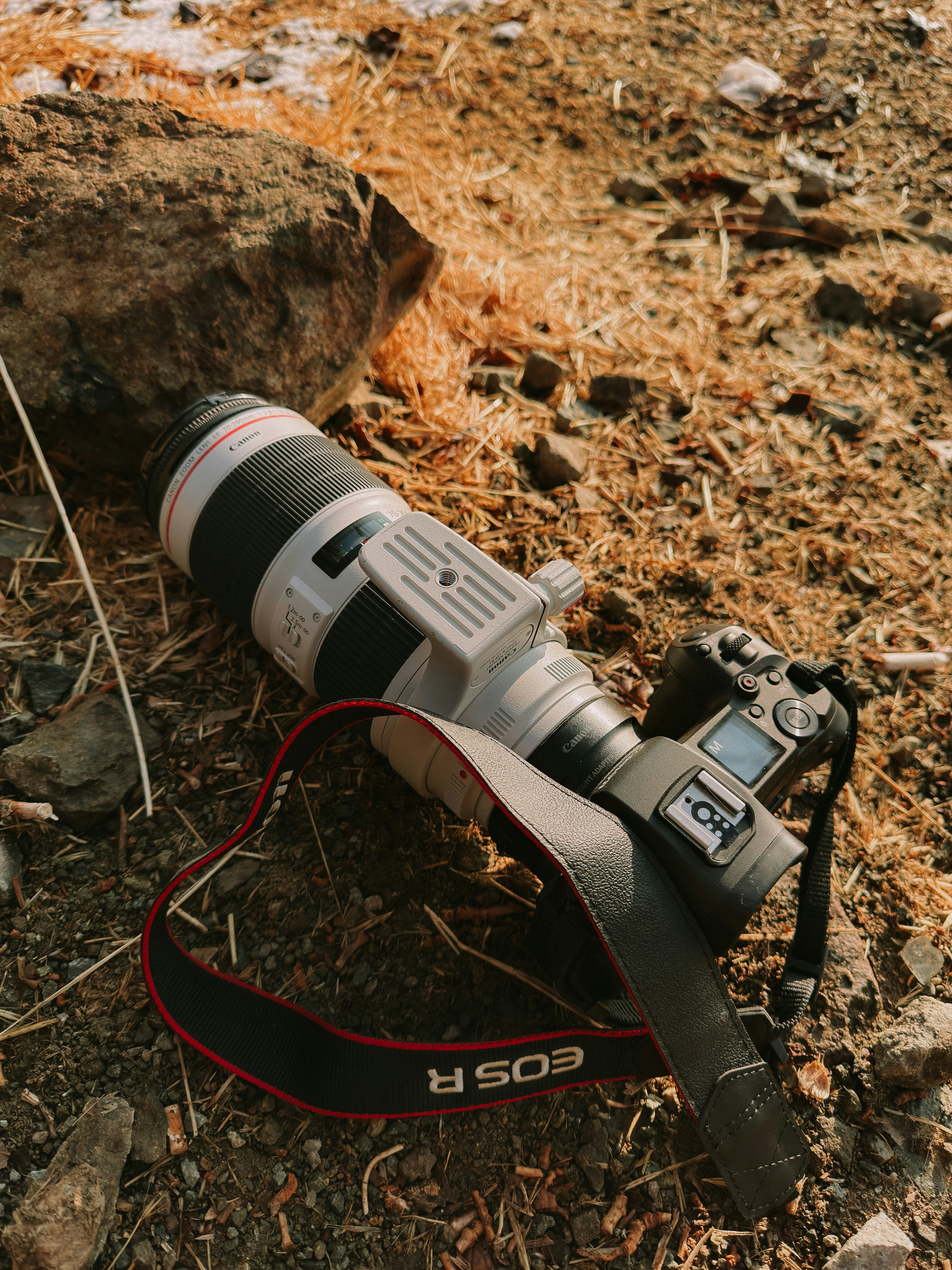 A camera with a large lens lies on the ground.