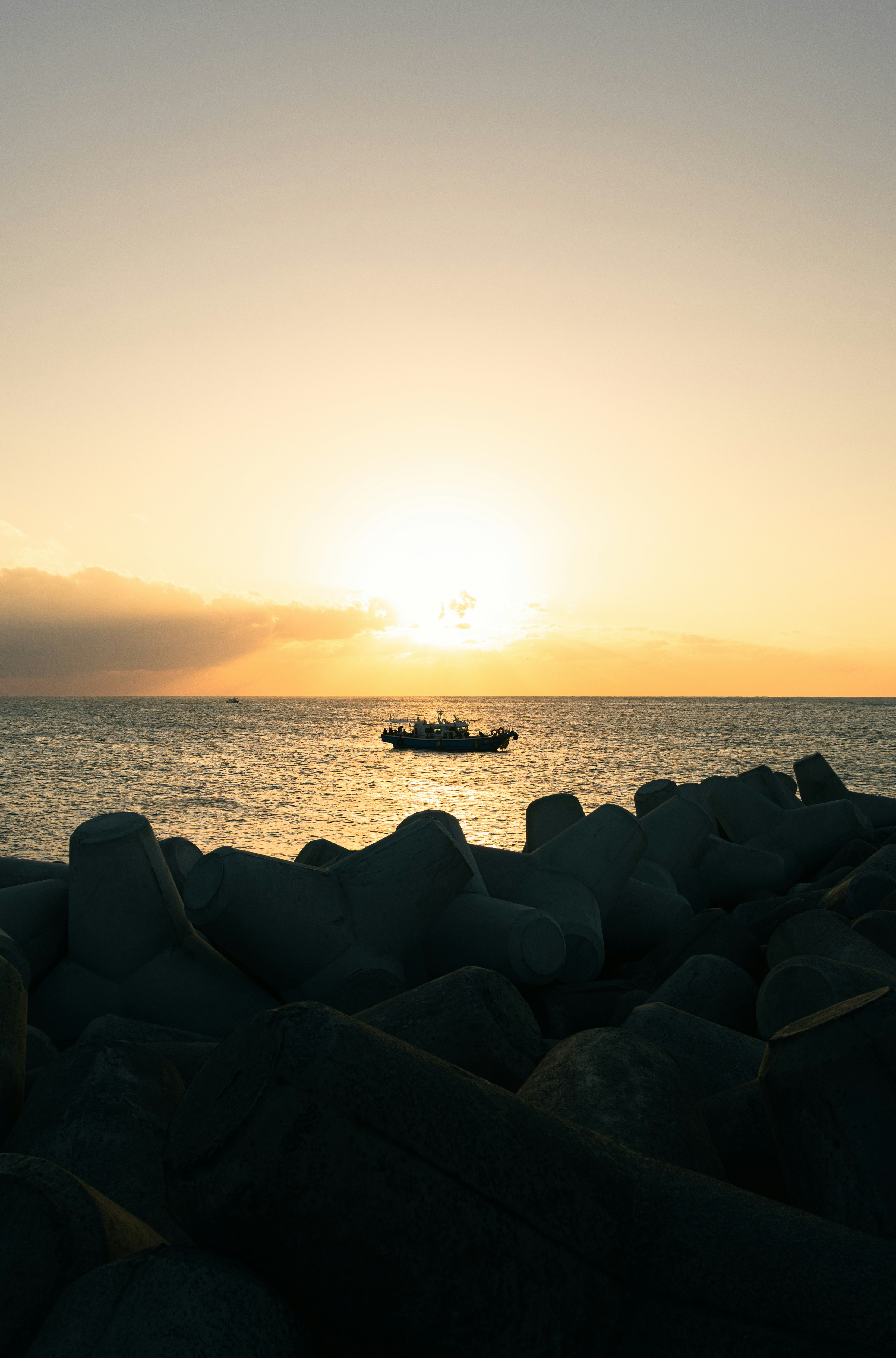 Boat on the ocean at sunset with breakwaters.