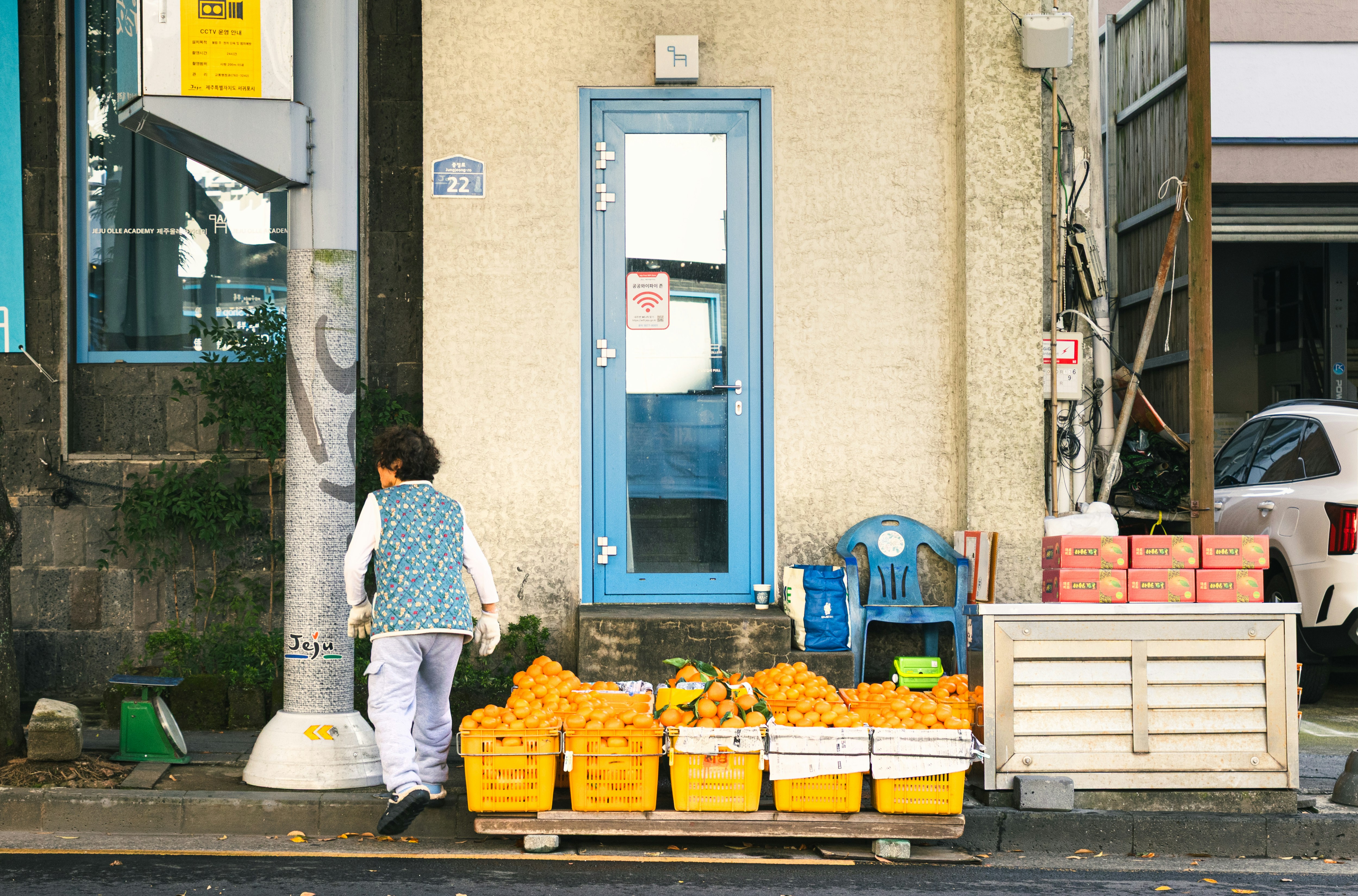 Woman walks past a flower stand on street.