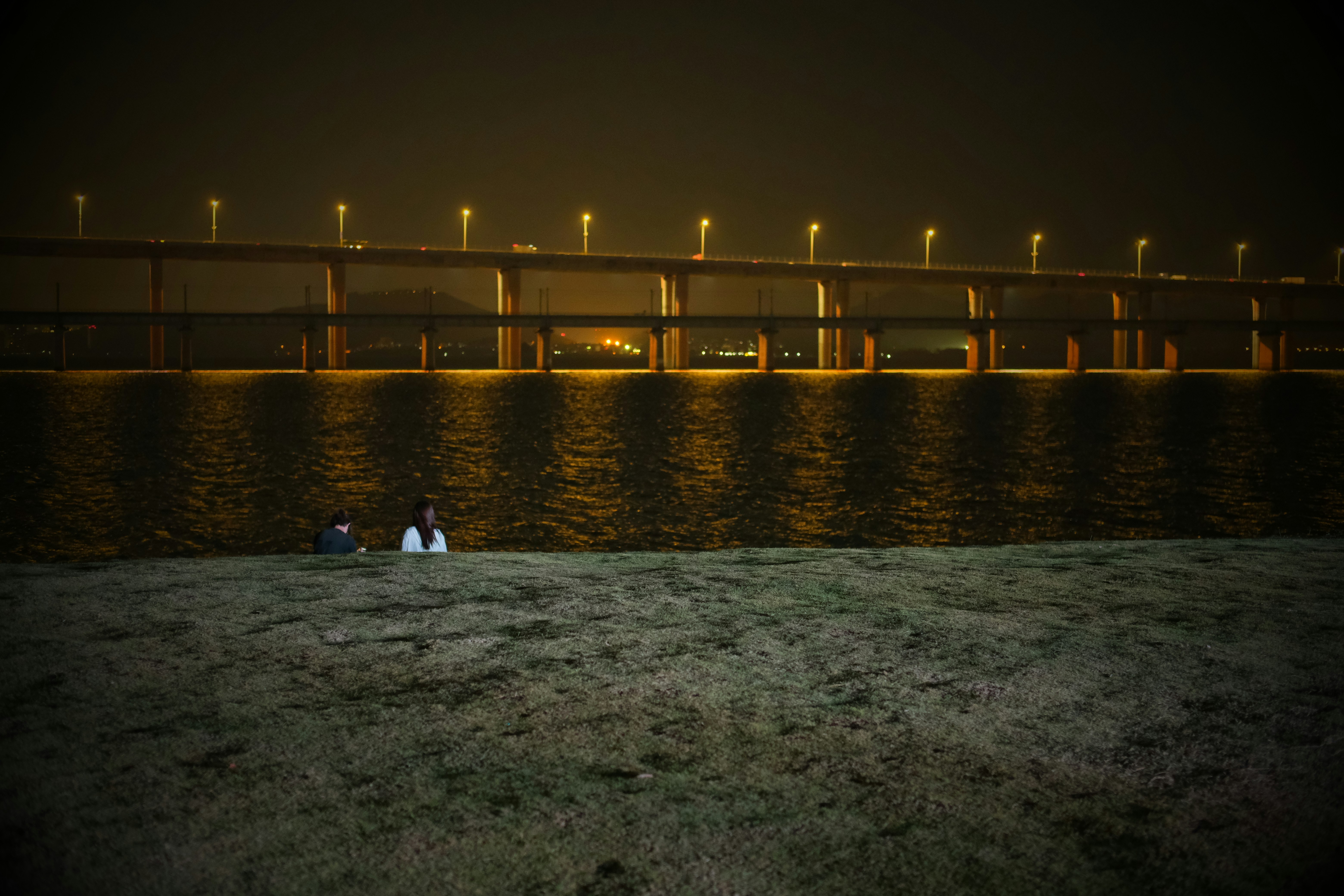 Bridge illuminated at night over a dark body of water
