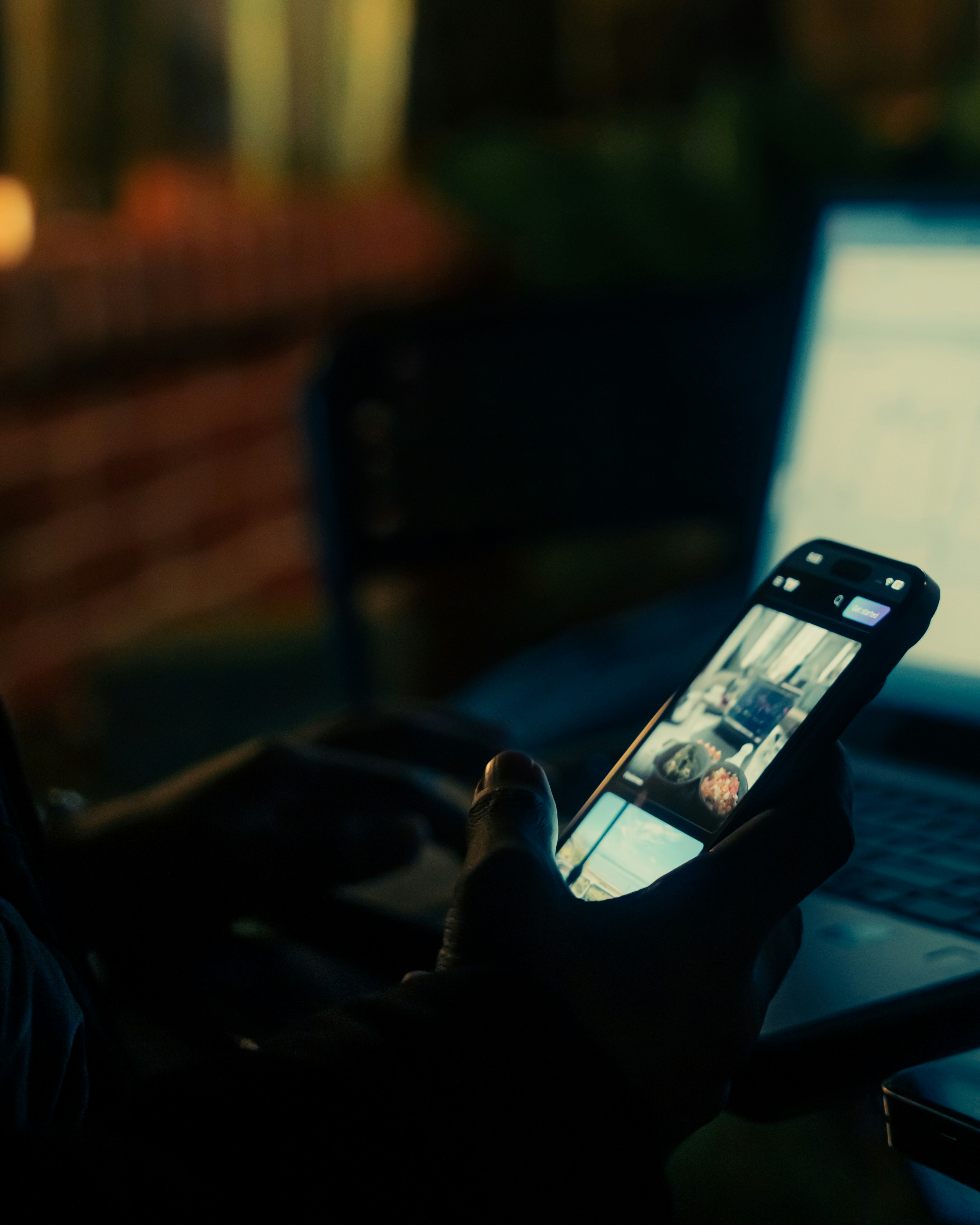 Person using smartphone and laptop at night.
