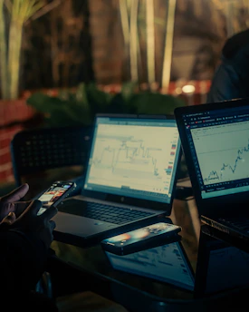 People working on laptops with financial charts at night.