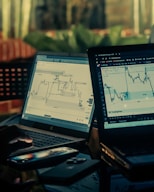 Two laptops displaying stock market charts