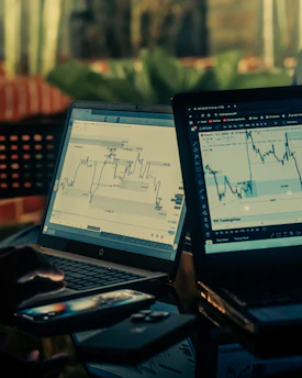 Two laptops displaying stock market charts