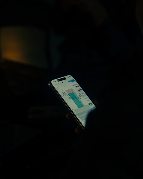 Hand holding smartphone displaying stock market chart.