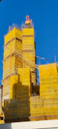Tall building under construction covered in yellow netting.