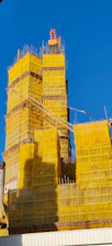 Tall building under construction covered in yellow netting.