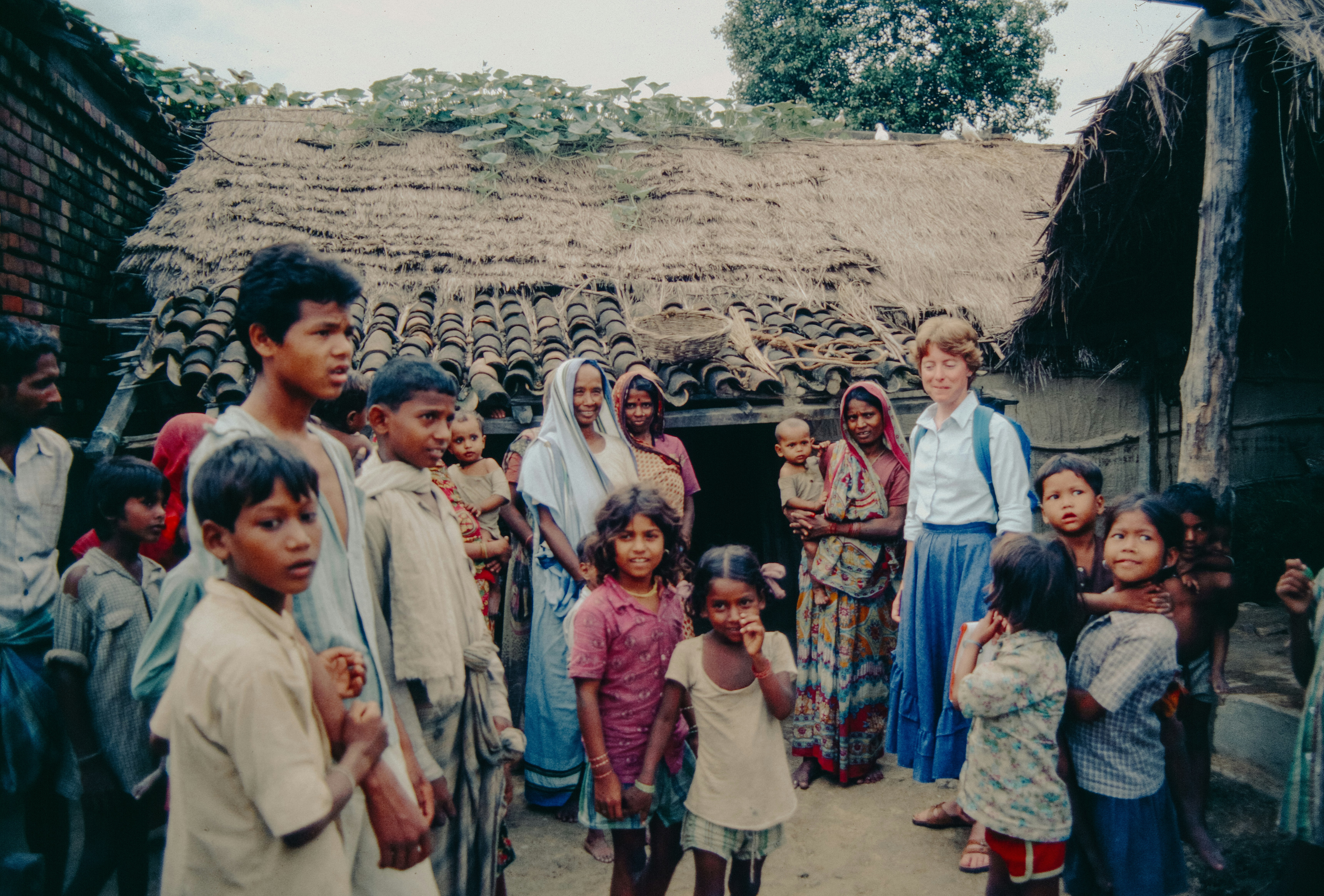 A diverse group of tribal people in traditional attire, perhaps at a village meeting, looking engaged in a discussion with a sense of community.
