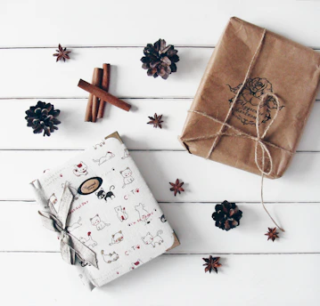 Two wrapped gifts with decorative accents on white wood