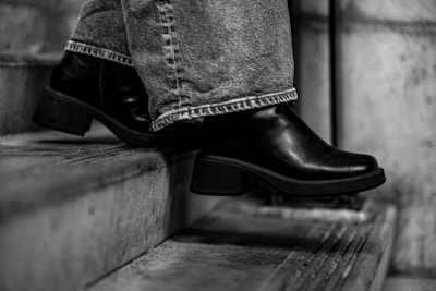 A person walks down stairs in black boots.