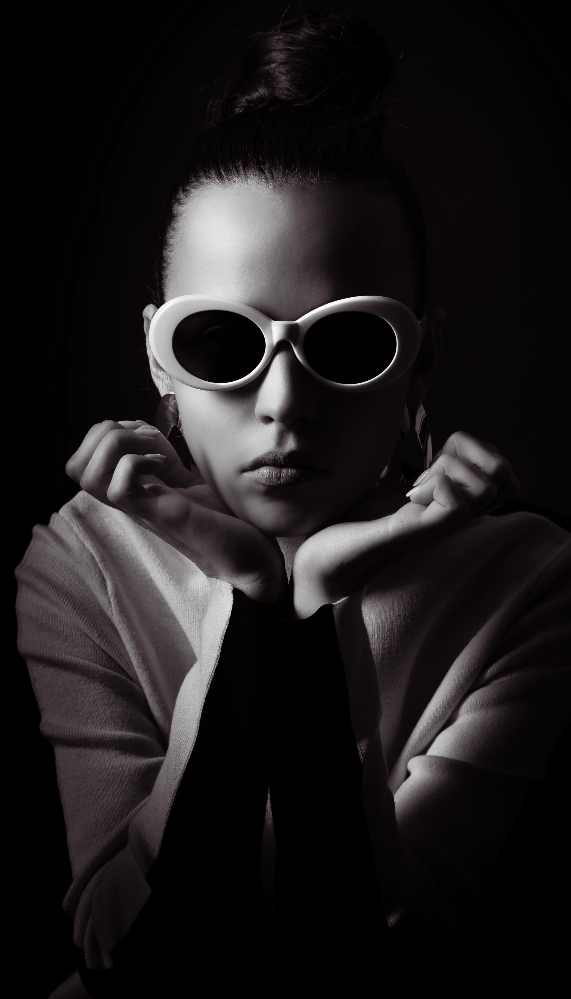 Woman with sunglasses and hair bun in dark background