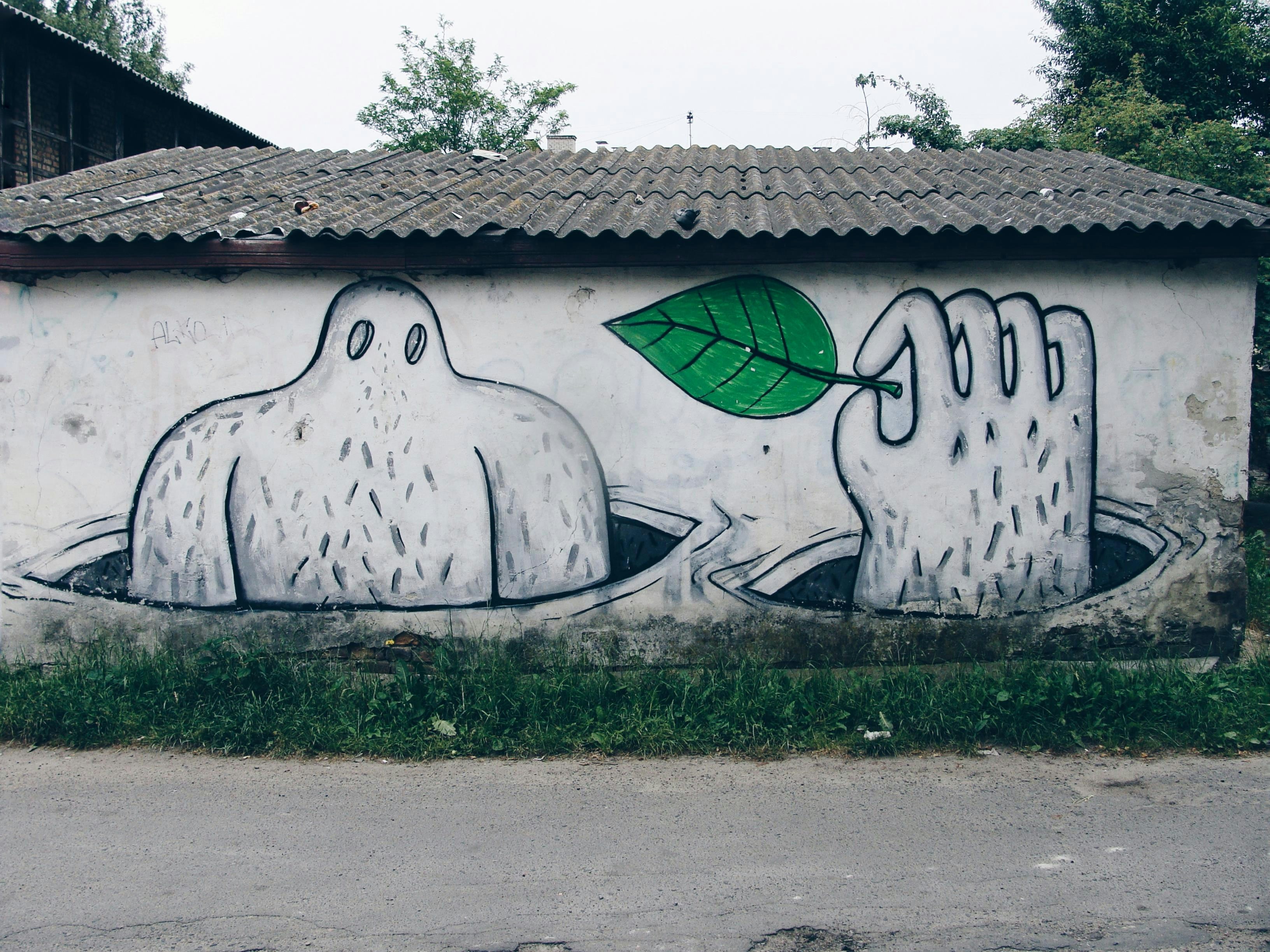 Graffiti art of a ghost and hand holding a leaf.