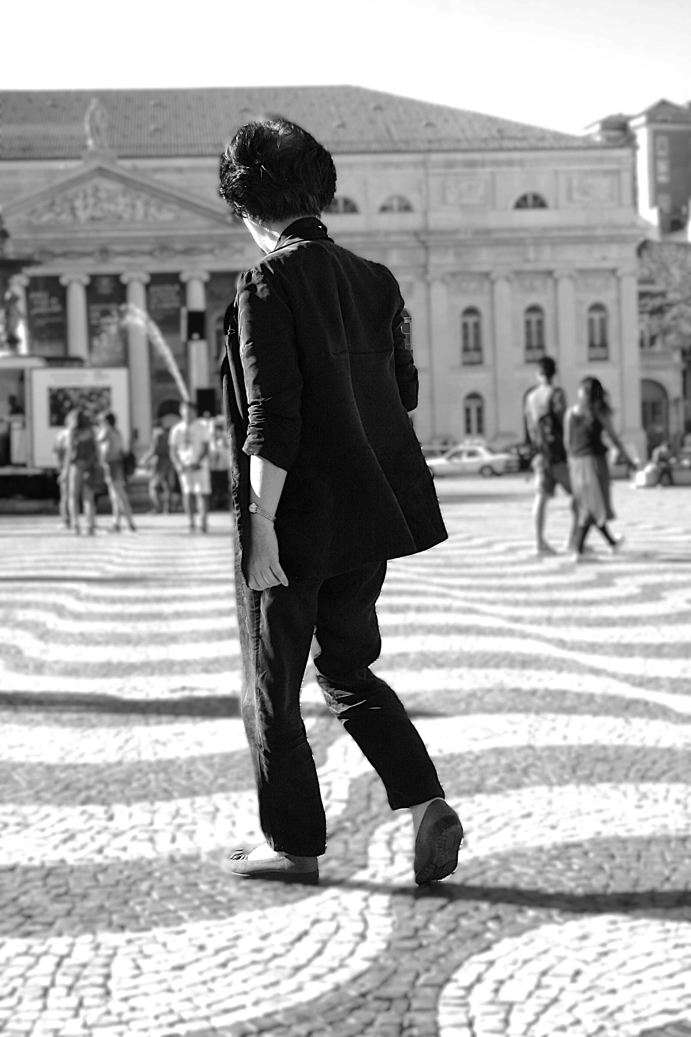 Person walking across patterned pavement in city square