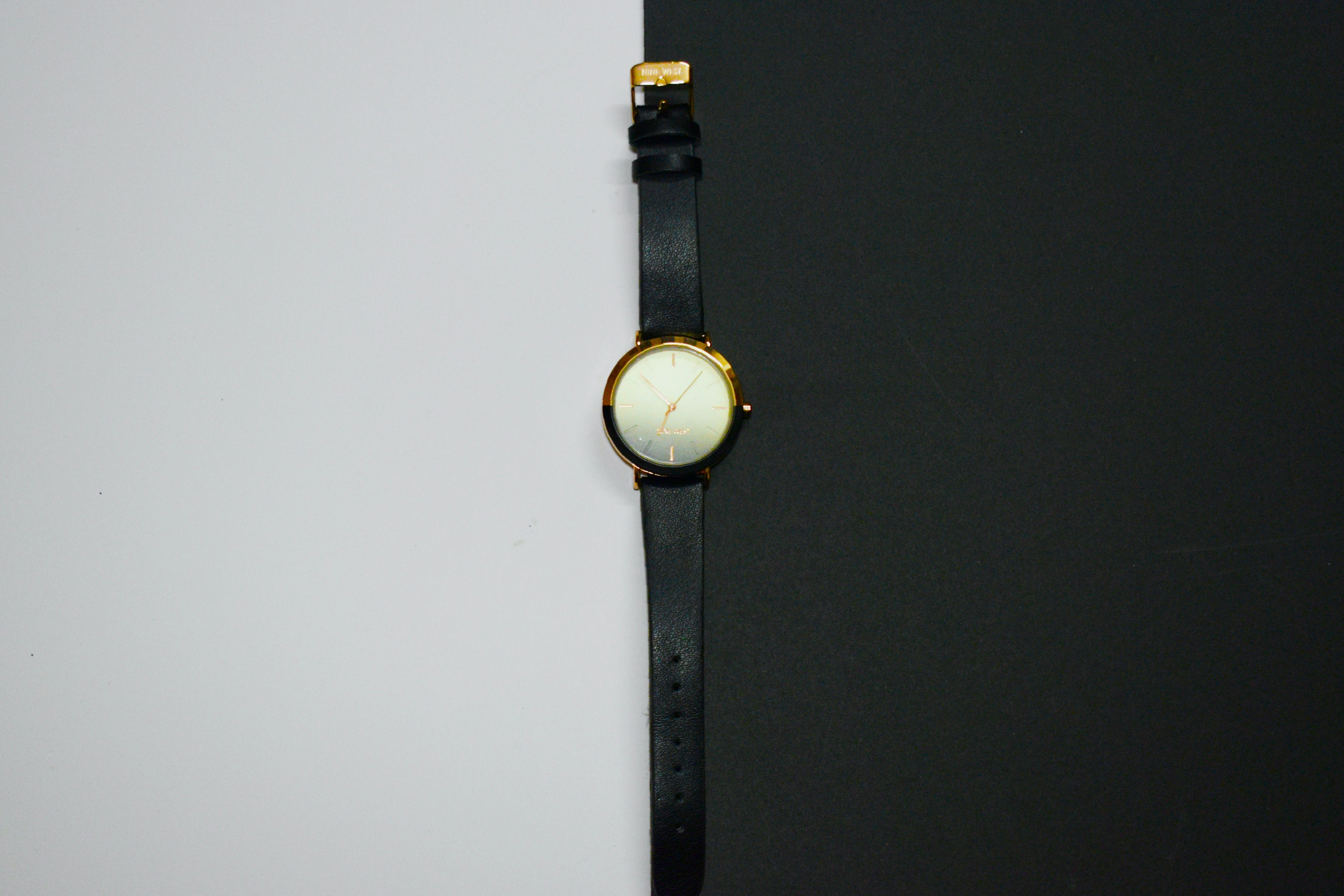A black leather watch on a split background