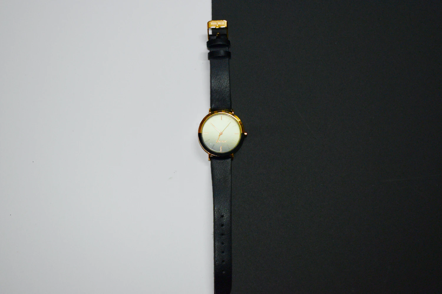 Sentier 34, a small gold-tone watch with a champagne dial on a black calf strap, half on white, half on black — in stock