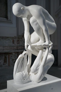 White marble sculpture of two figures in dynamic pose