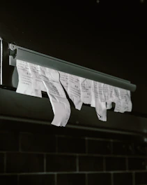 Torn receipts hanging from a metal dispenser.