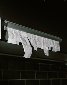 Torn receipts hanging from a metal dispenser.