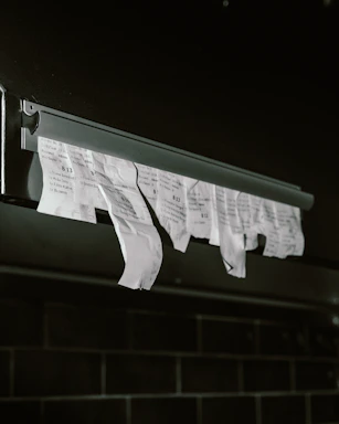 Torn receipts hanging from a metal dispenser.