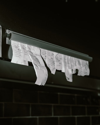 Torn receipts hanging from a metal dispenser.